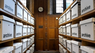 Rows of white archive boxes on wooden shelves