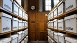 Rows of white archive boxes on wooden shelves