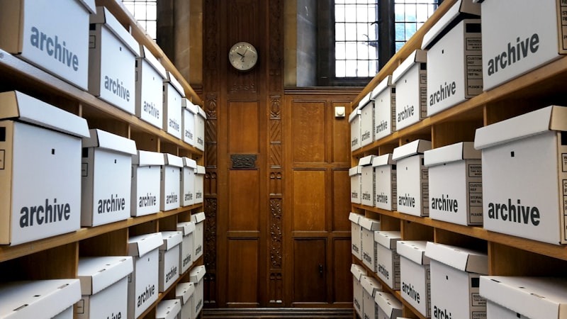 Rows of white archive boxes organised on wooden shelves