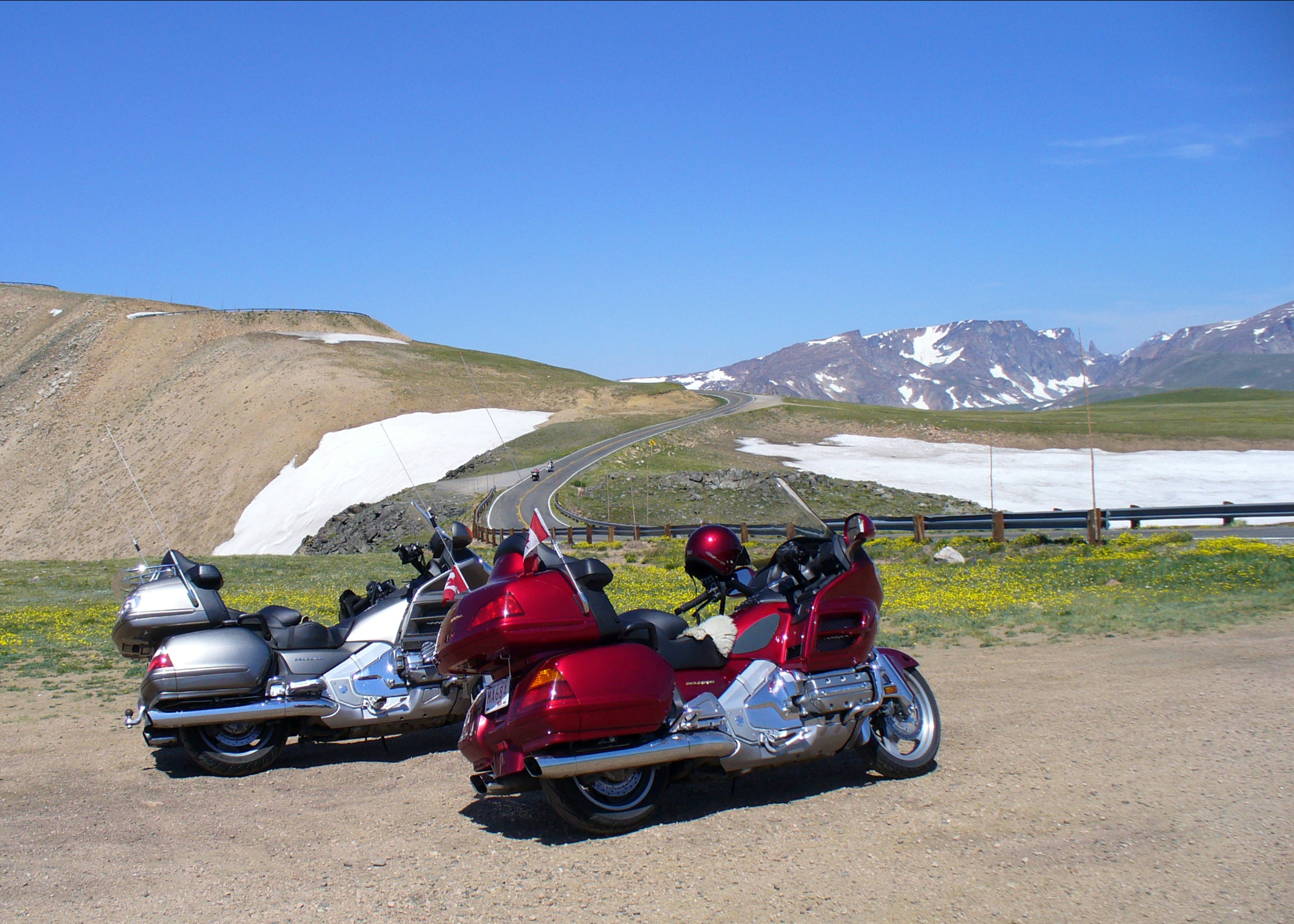 Two motorcycles parked with snowy mountains behind.