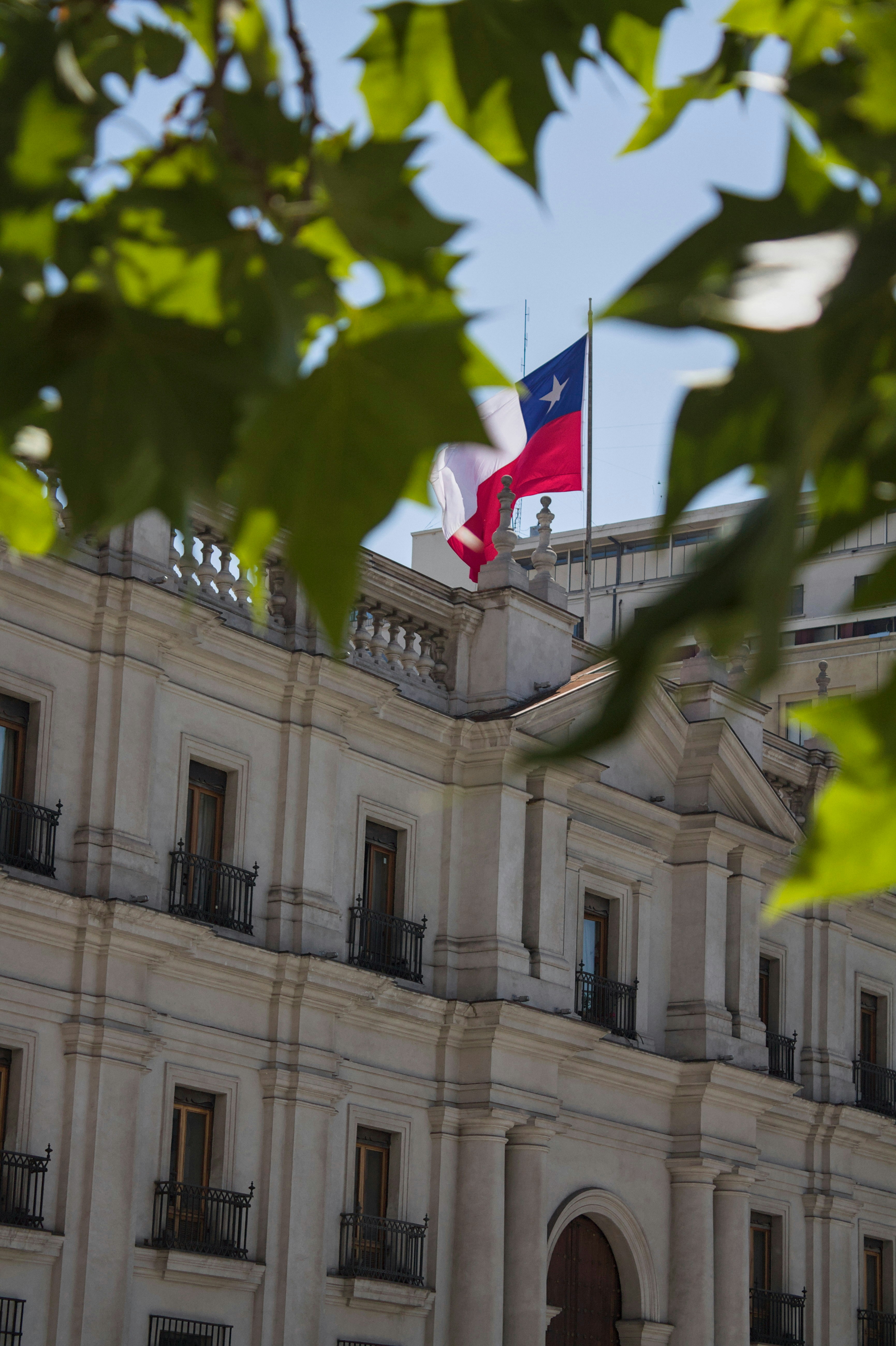 Edificio de piedra ornamentado con una bandera chilena en el tejado.