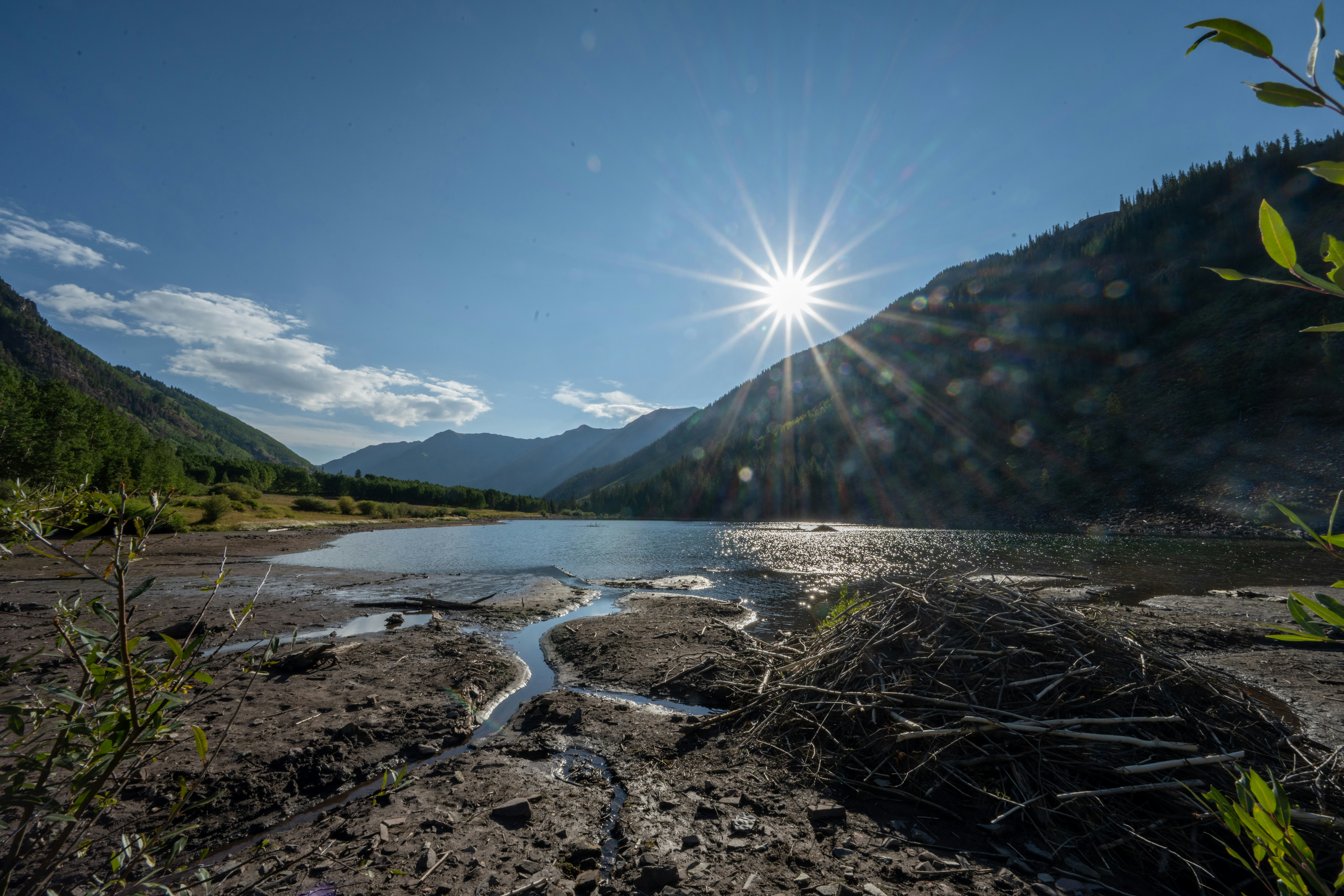 Die Sonne scheint hell über einer Bergseenlandschaft.