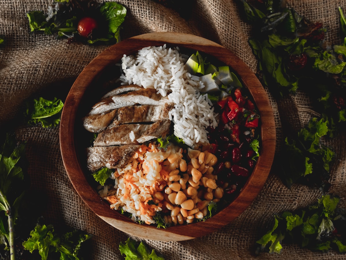나무 볼에 담긴 닭고기와 쌀, 콩이 어우러진 균형 식사