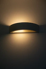 A modern wall sconce emitting warm light.