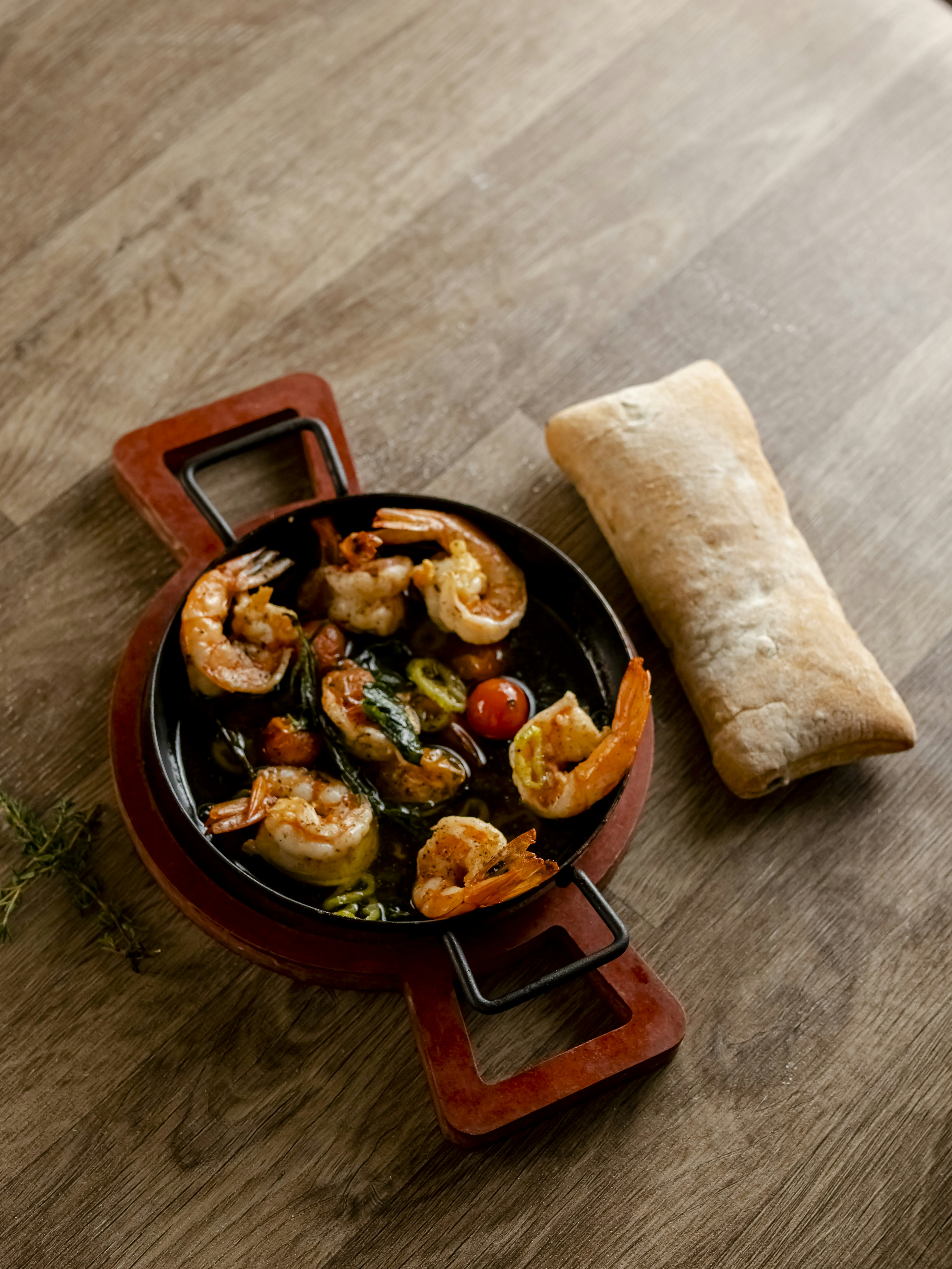 Shrimp and tomatoes served in a skillet with bread.