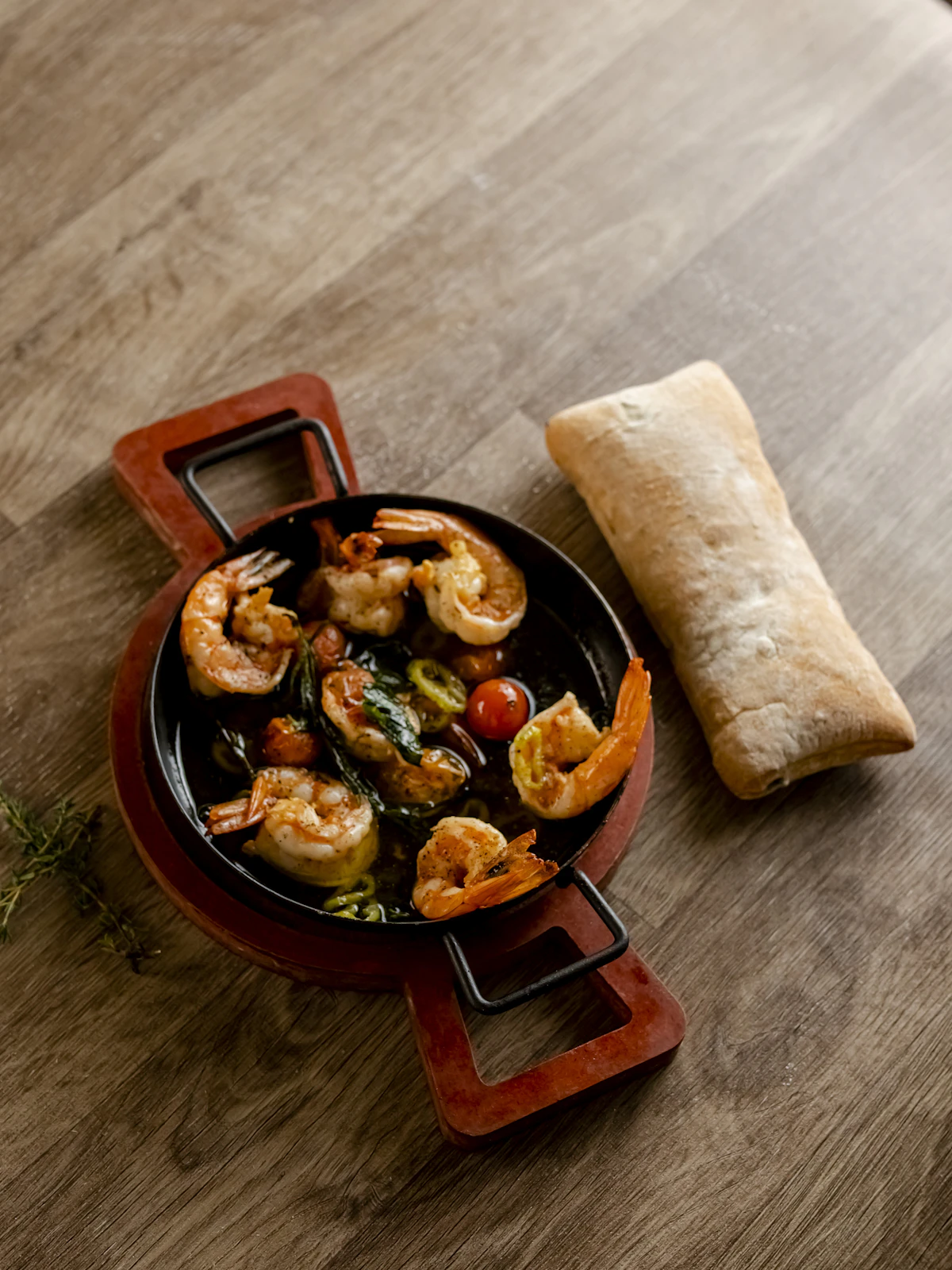Shrimp and tomatoes served in a skillet with bread