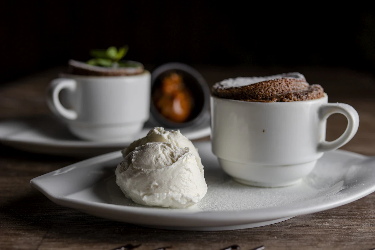 A risen chocolate soufflé dusted with icing sugar, served with a quenelle of cream and caramel.