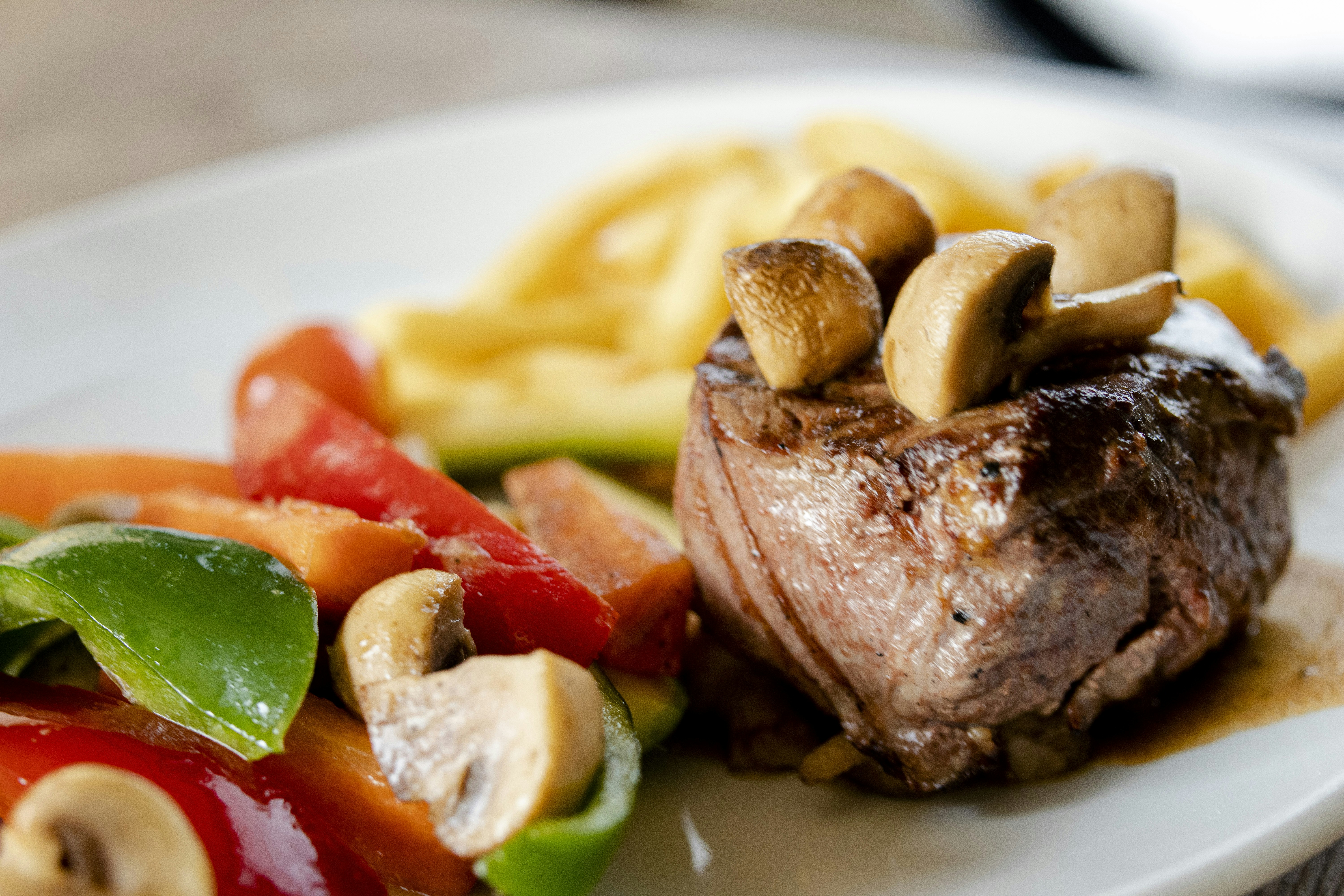Steak with mushrooms and colorful vegetables on a plate.
