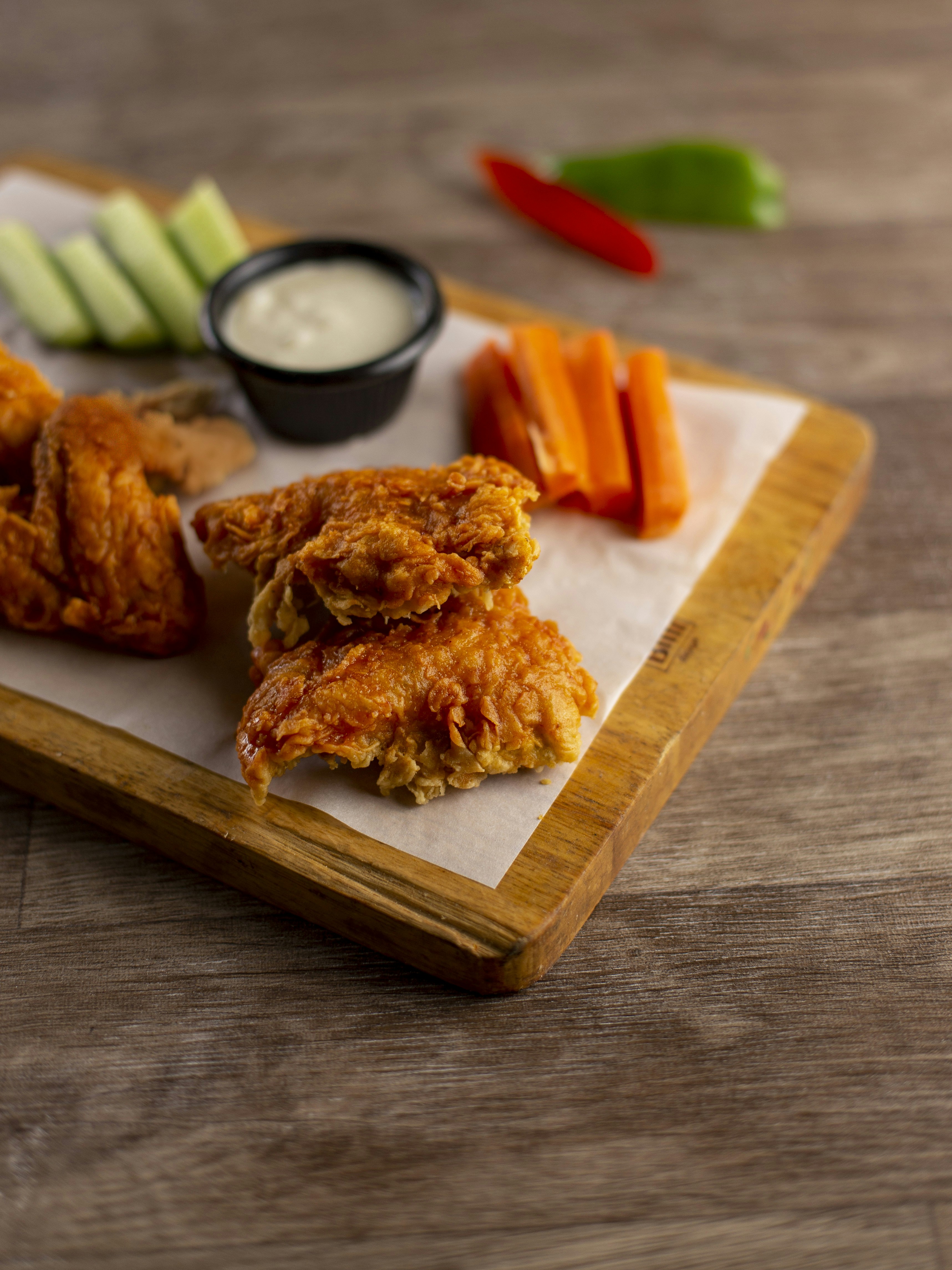 Crispy fried chicken wings with dipping sauce and vegetables.