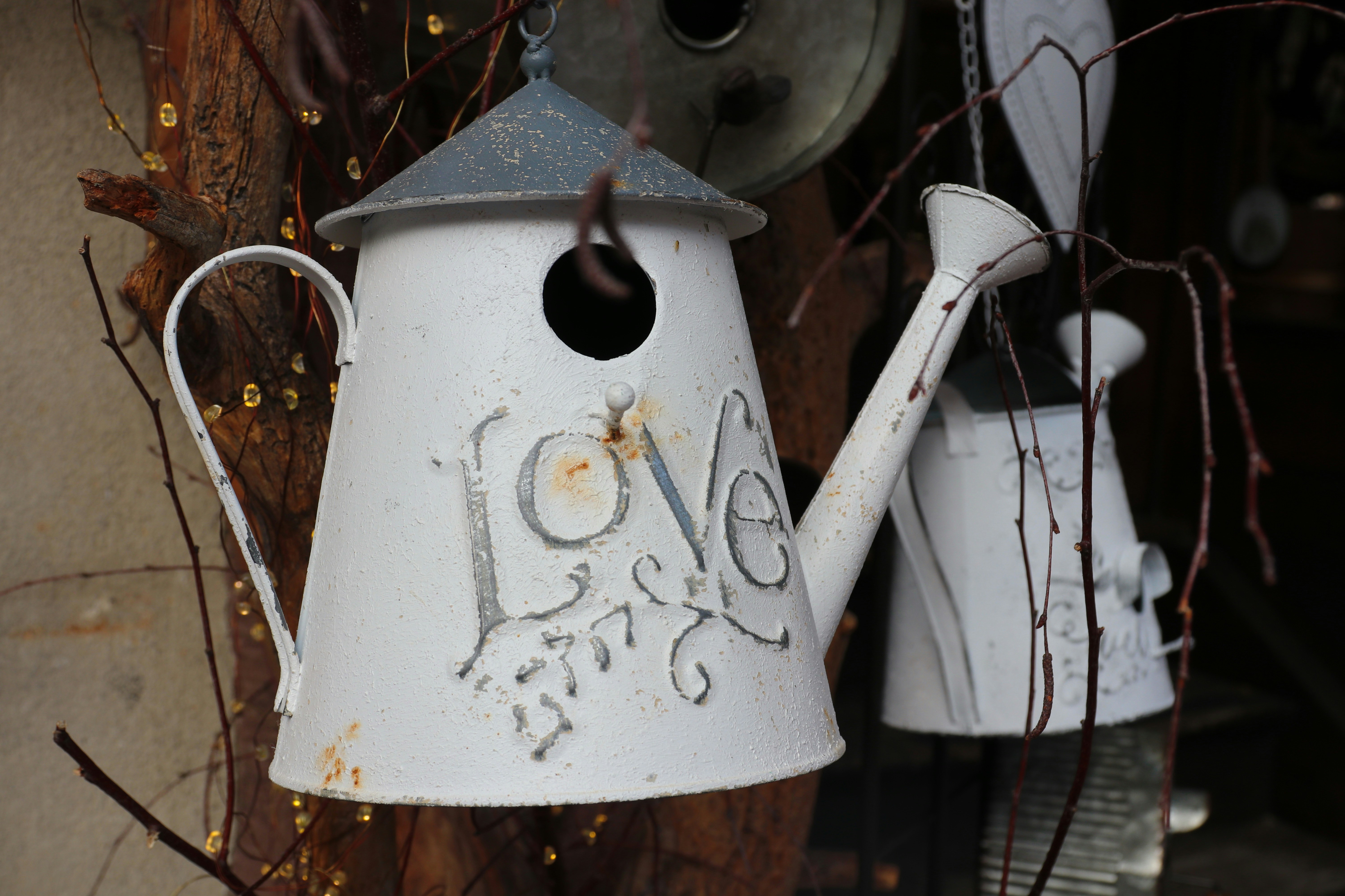 White watering can birdhouse with "love" design.