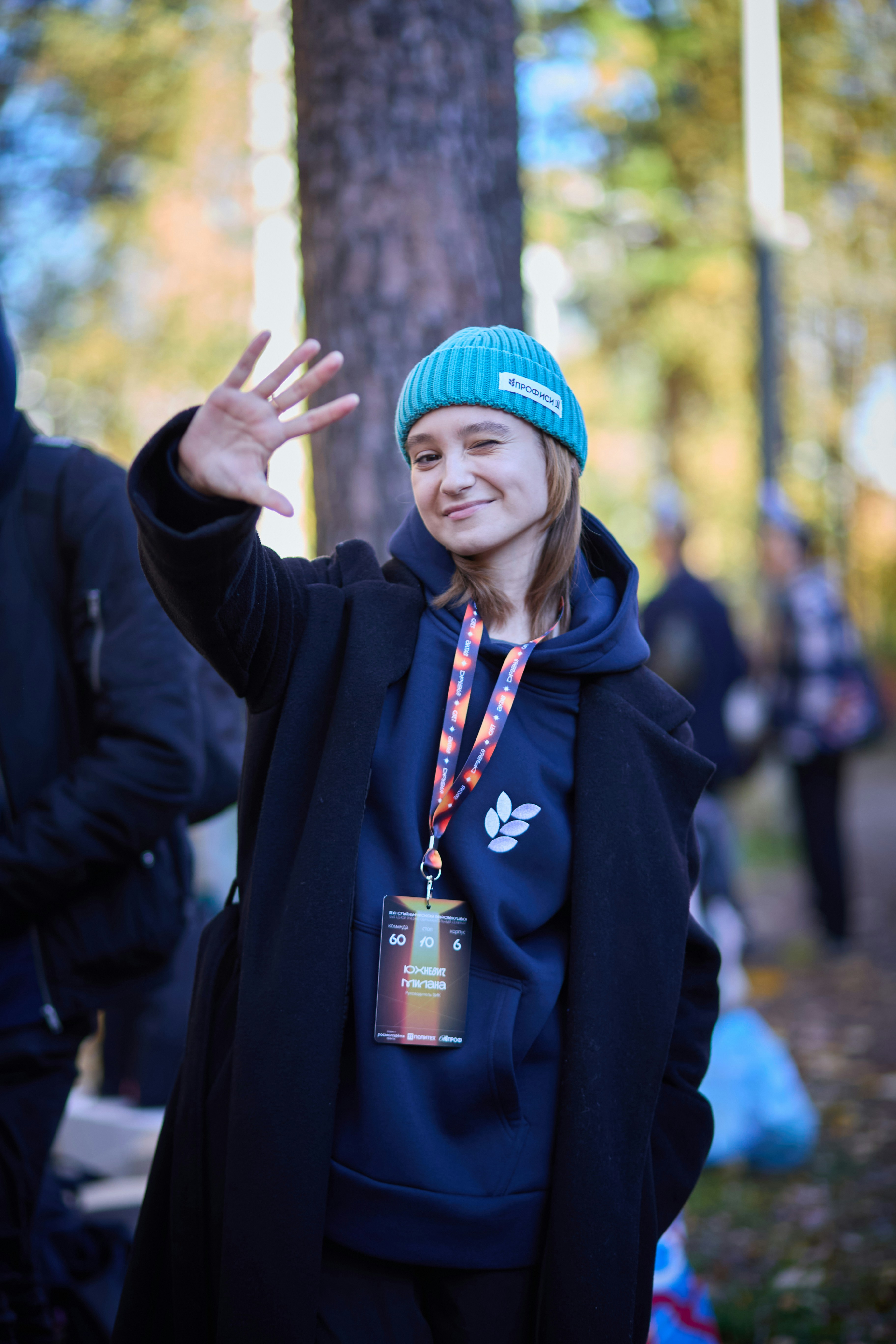 Una giovane donna con un berretto blu saluta.