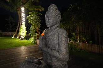 Stone buddha statue with hands clasped in prayer