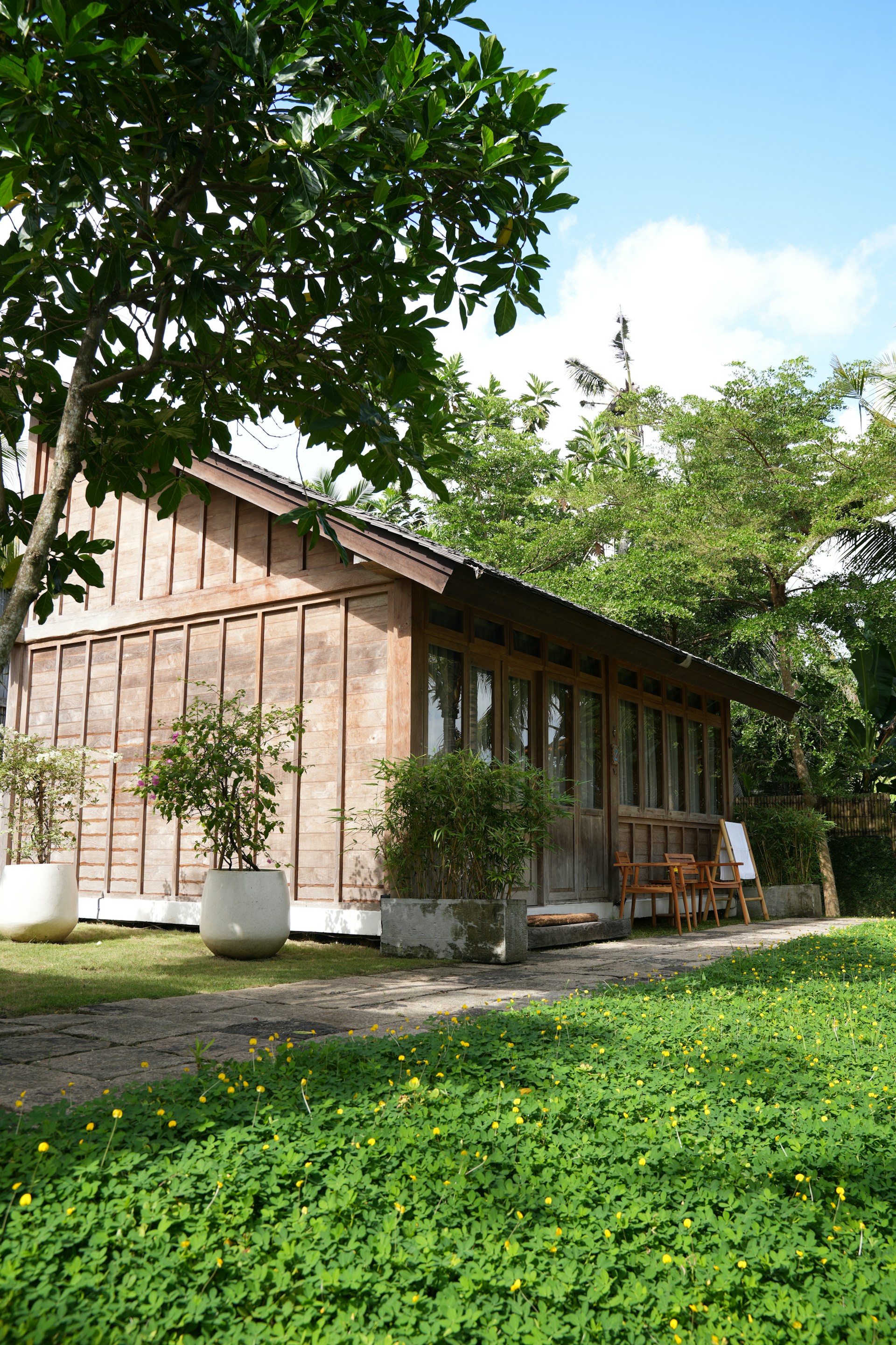 Wooden cabin surrounded by lush green trees and grass.