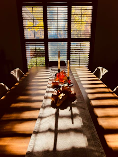 Dining table with autumn foliage visible through window