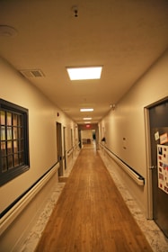Long assisted living hallway with wooden floor and doors.