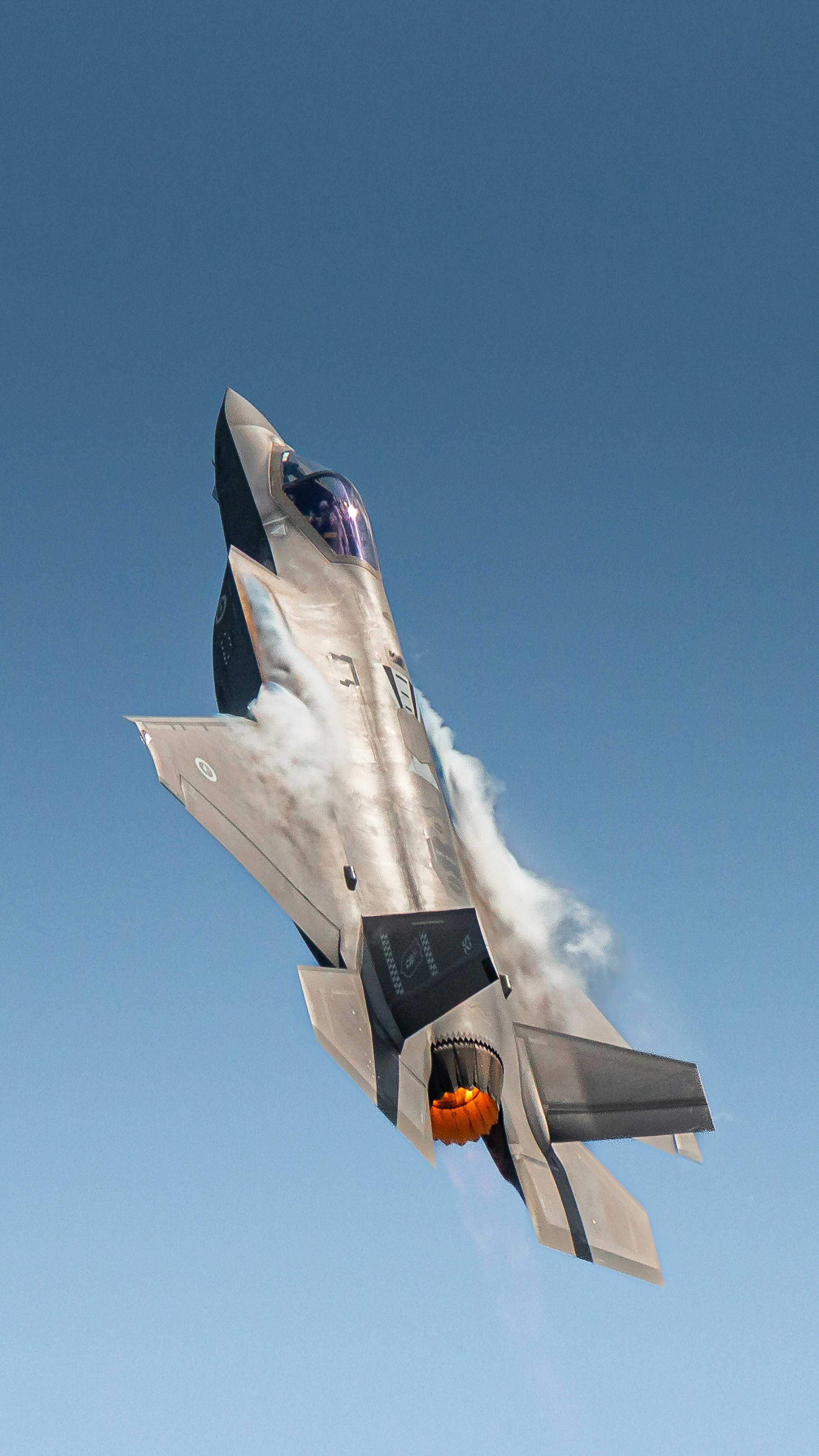 Fighter jet performs a maneuver against a clear blue sky