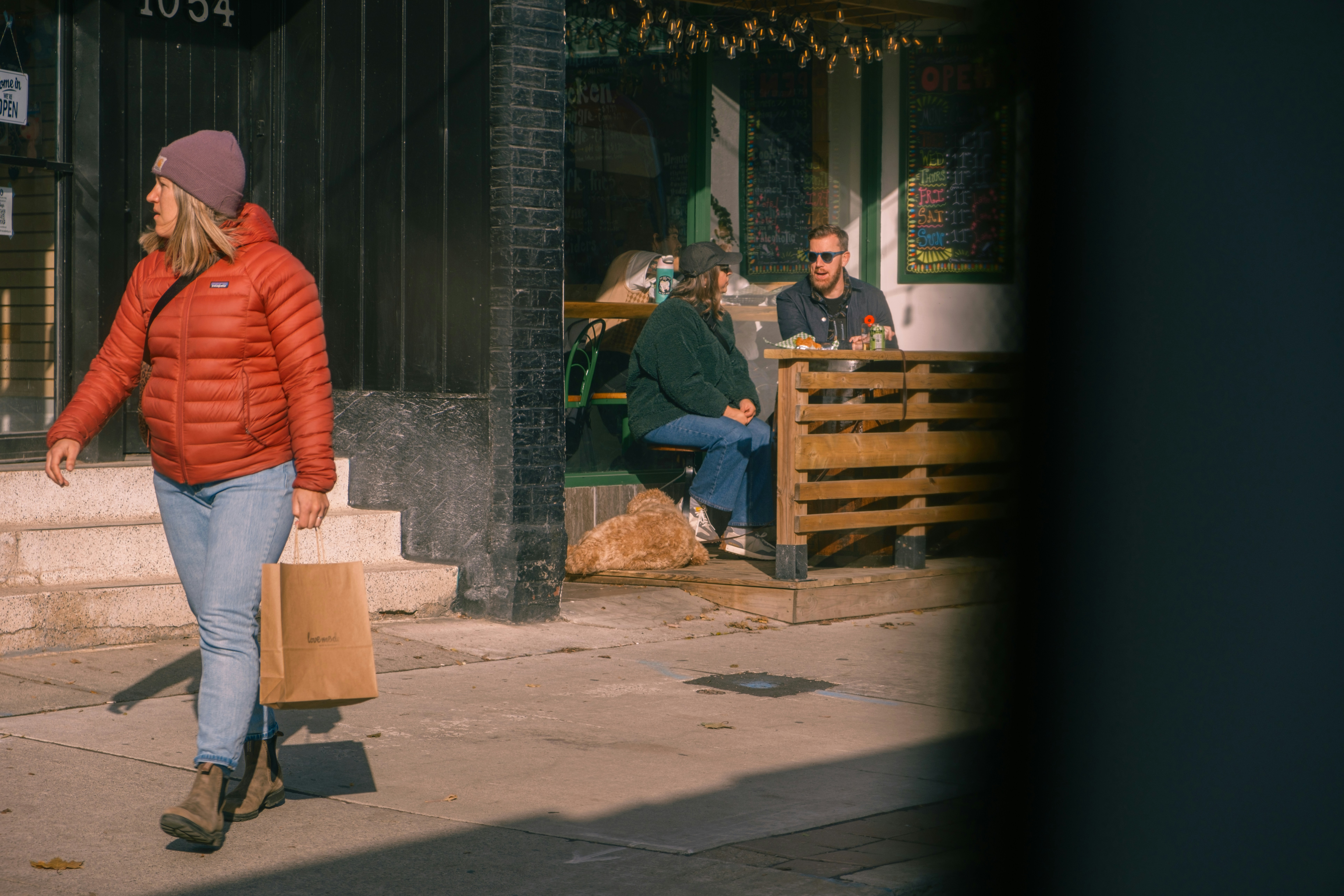 Woman walks past cafe with patrons seated outside