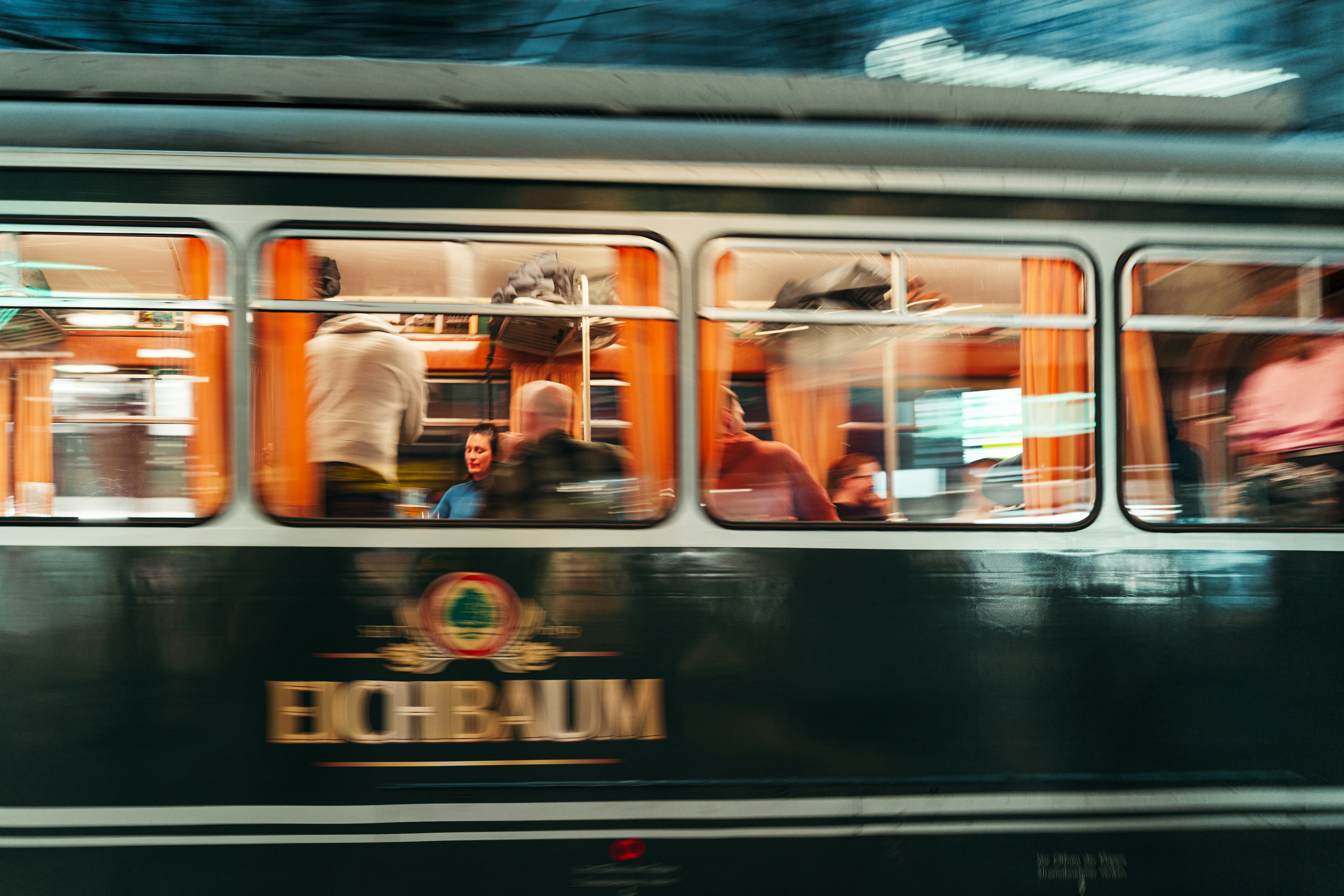 People inside a moving tram with orange curtains.