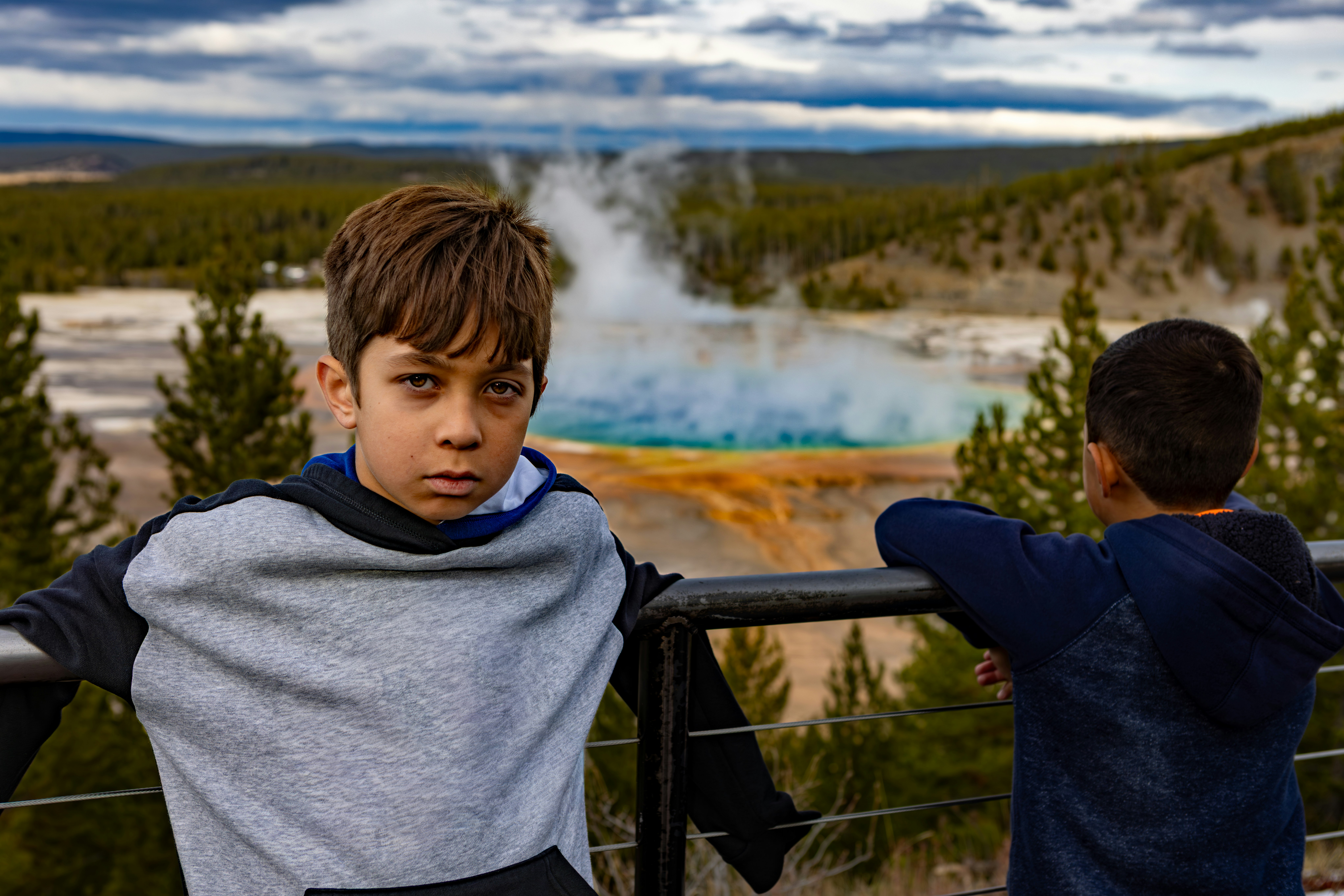Two boys looking at a colorful hot spring