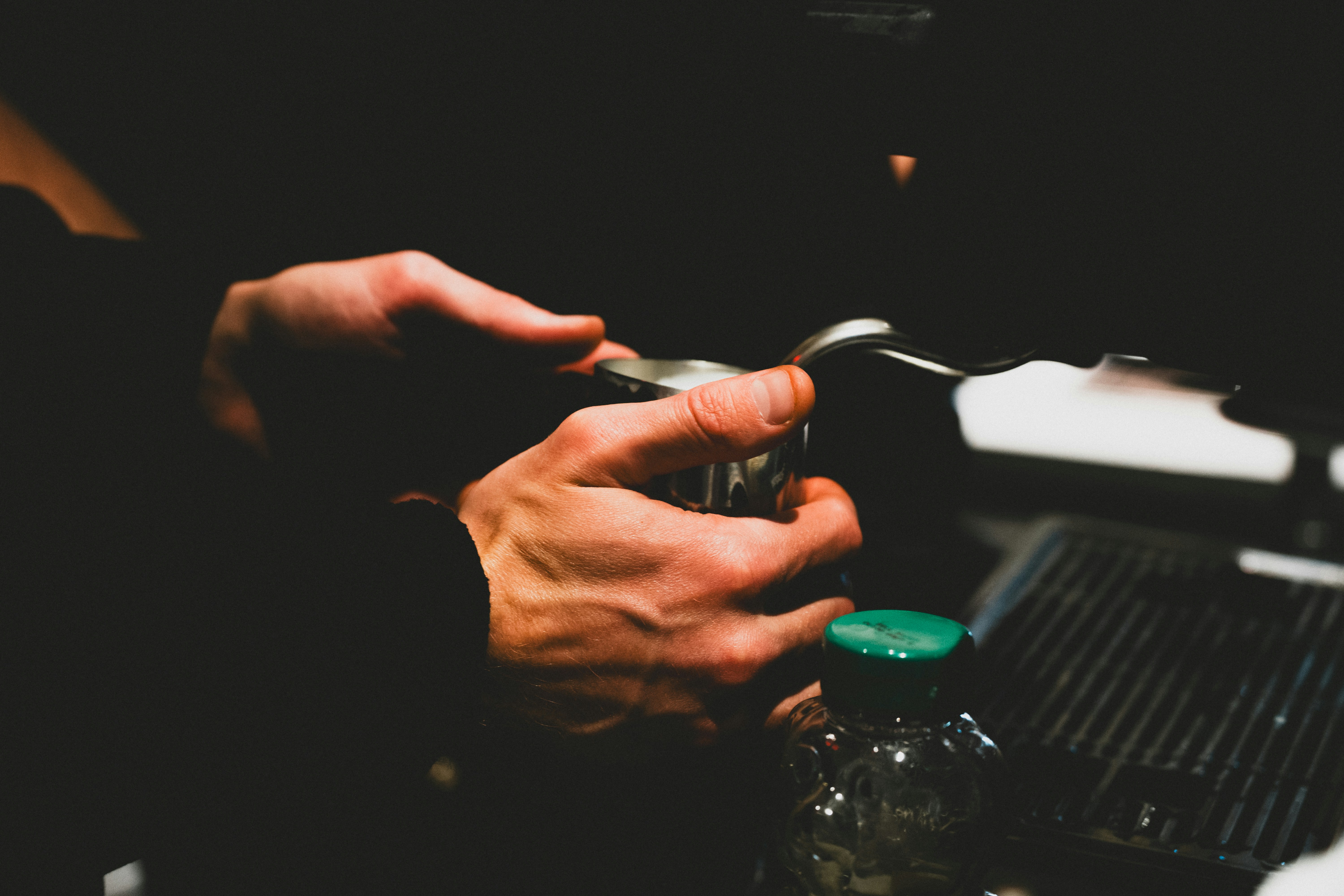 Barista hands holding steaming pitcher