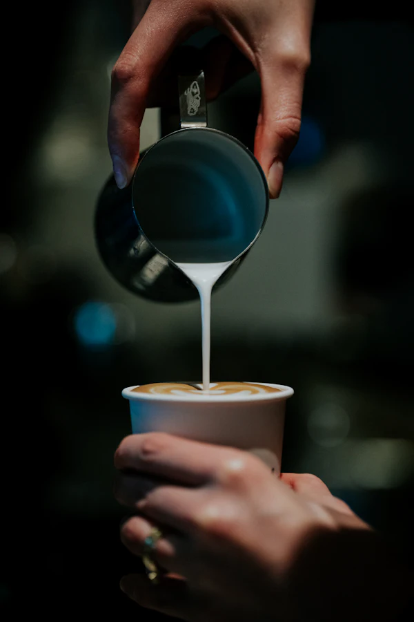 A barista pouring milk into a latte