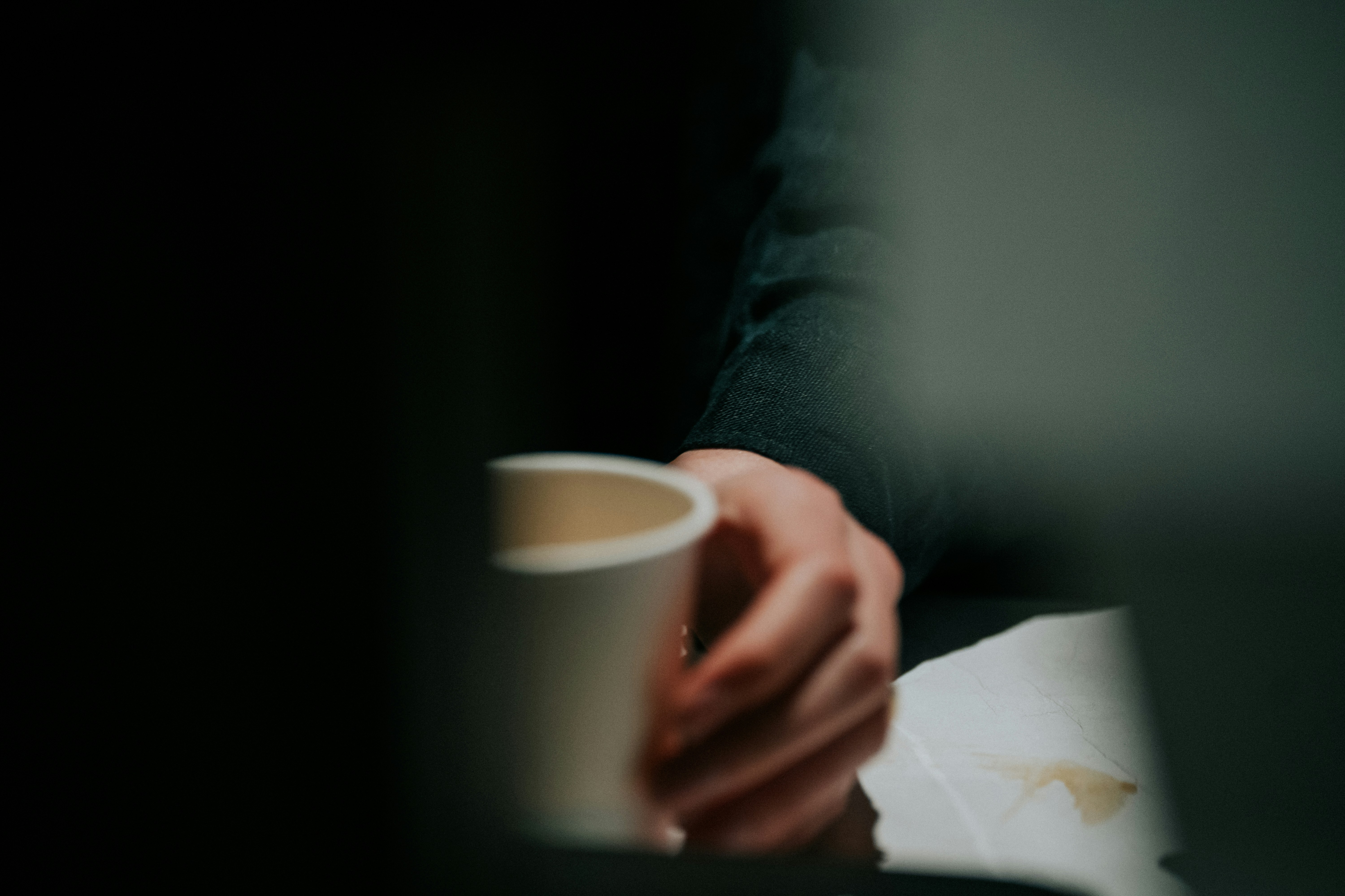 Hand reaching for a disposable coffee cup