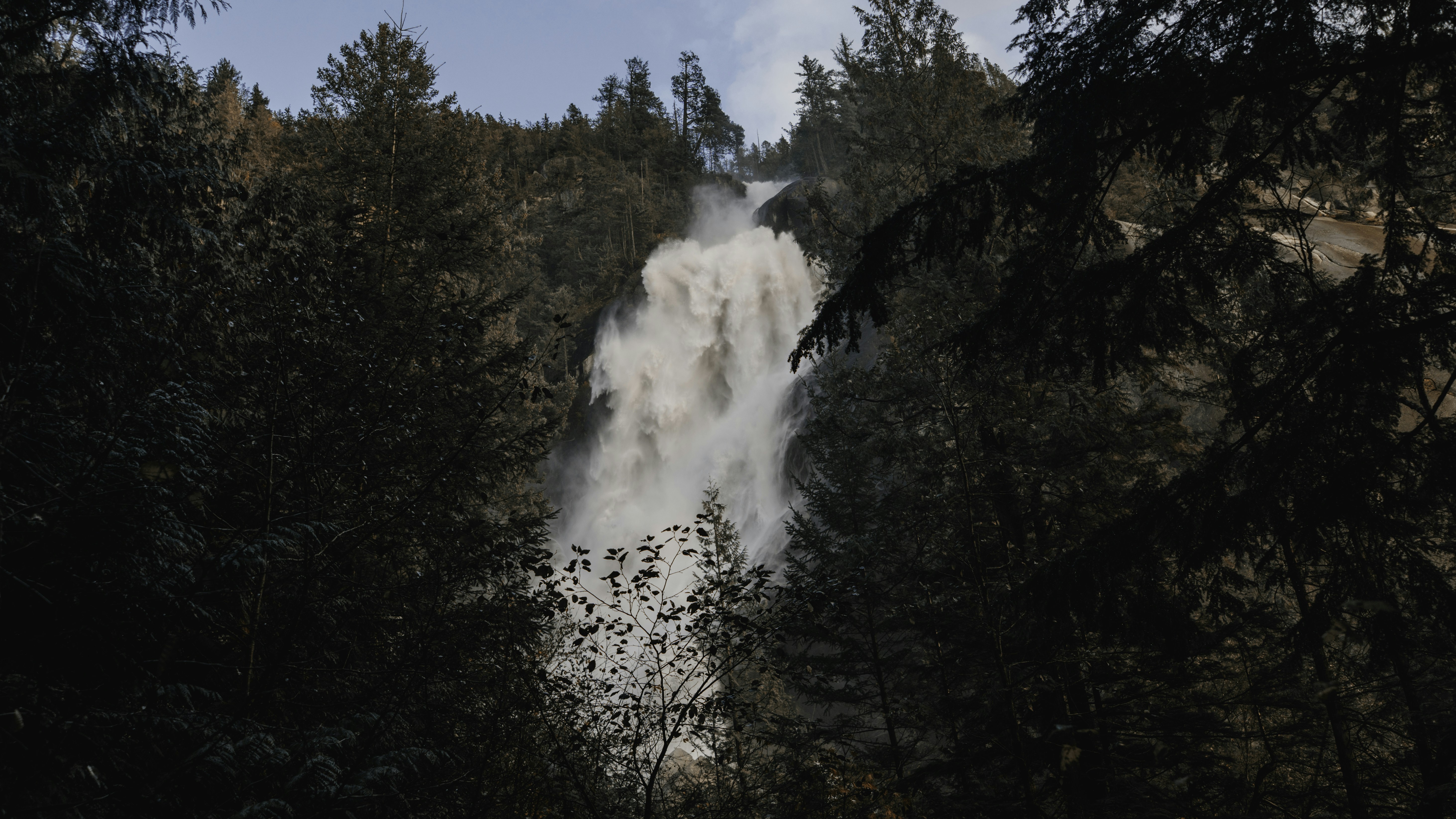 A powerful waterfall cascades through a dense forest.