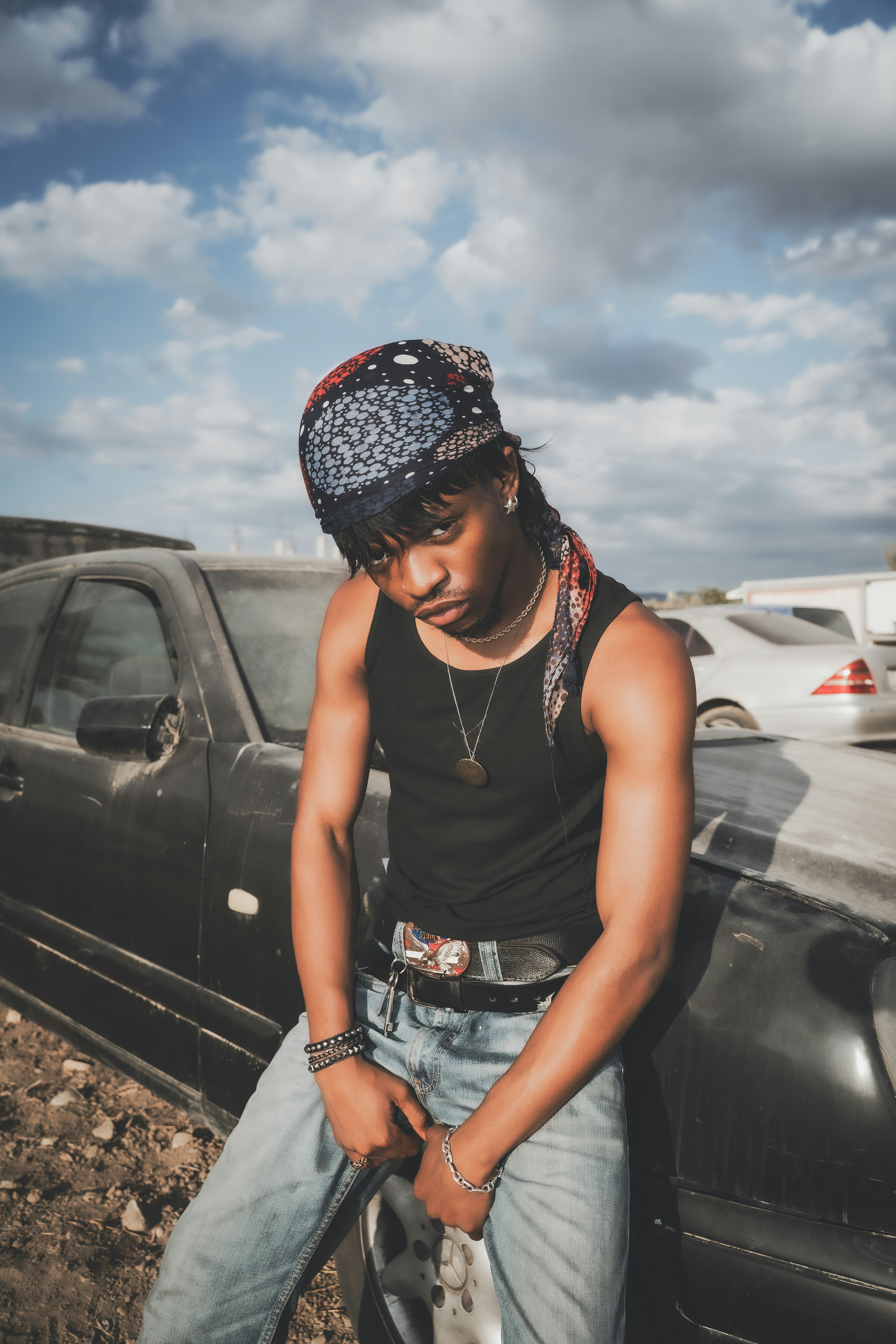 man in a junkyard behind a car