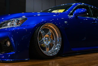 A shiny blue custom car with chrome wheels.