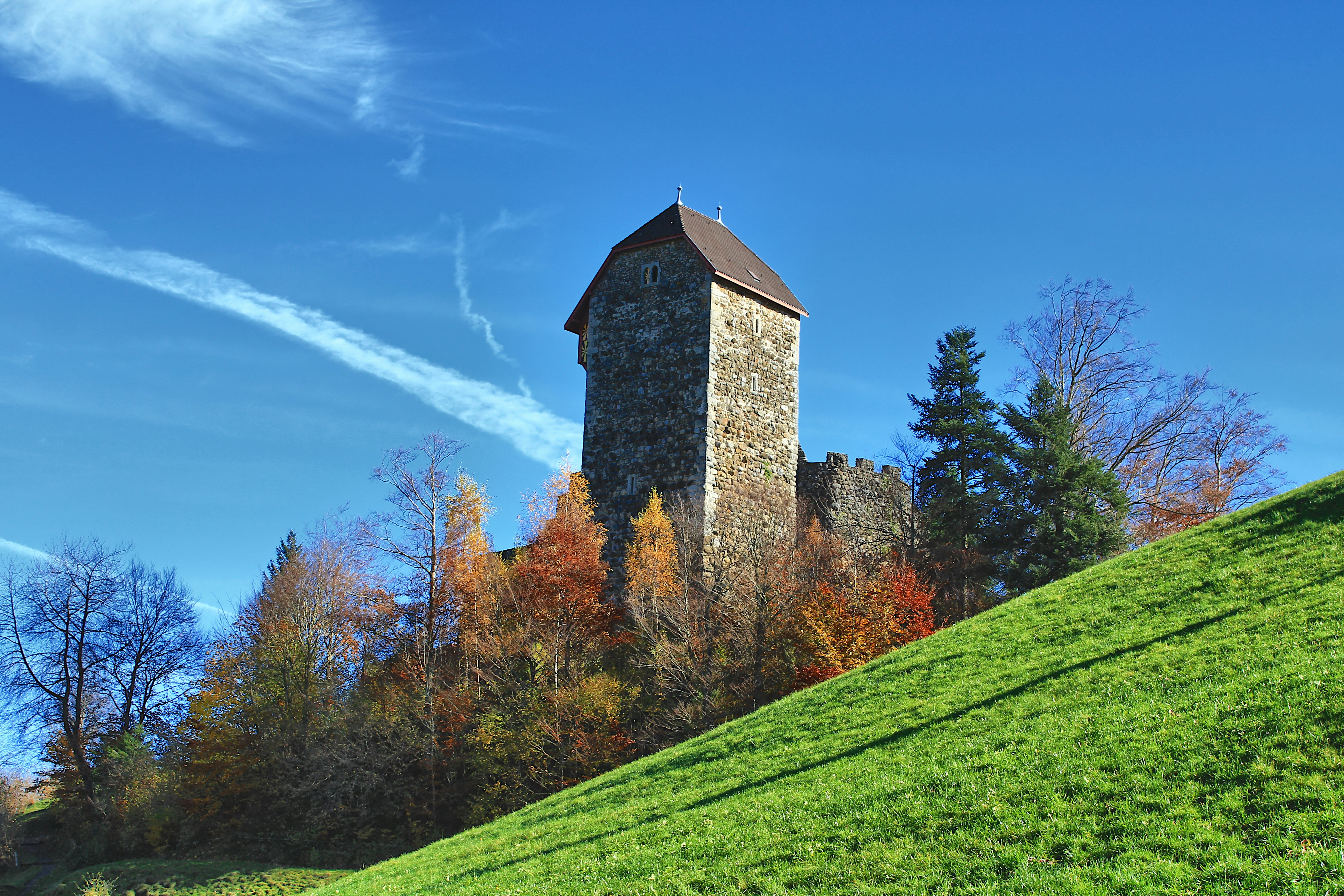Stone tower on a hill with autumn trees.