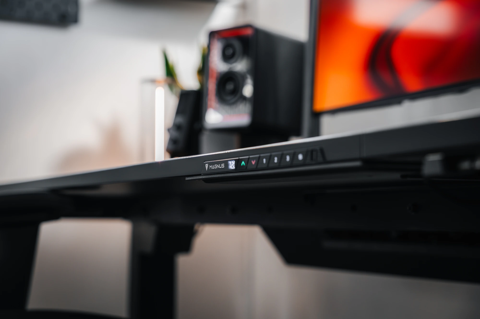 Adjustable standing desk workstation with monitor and desk controls in a modern office