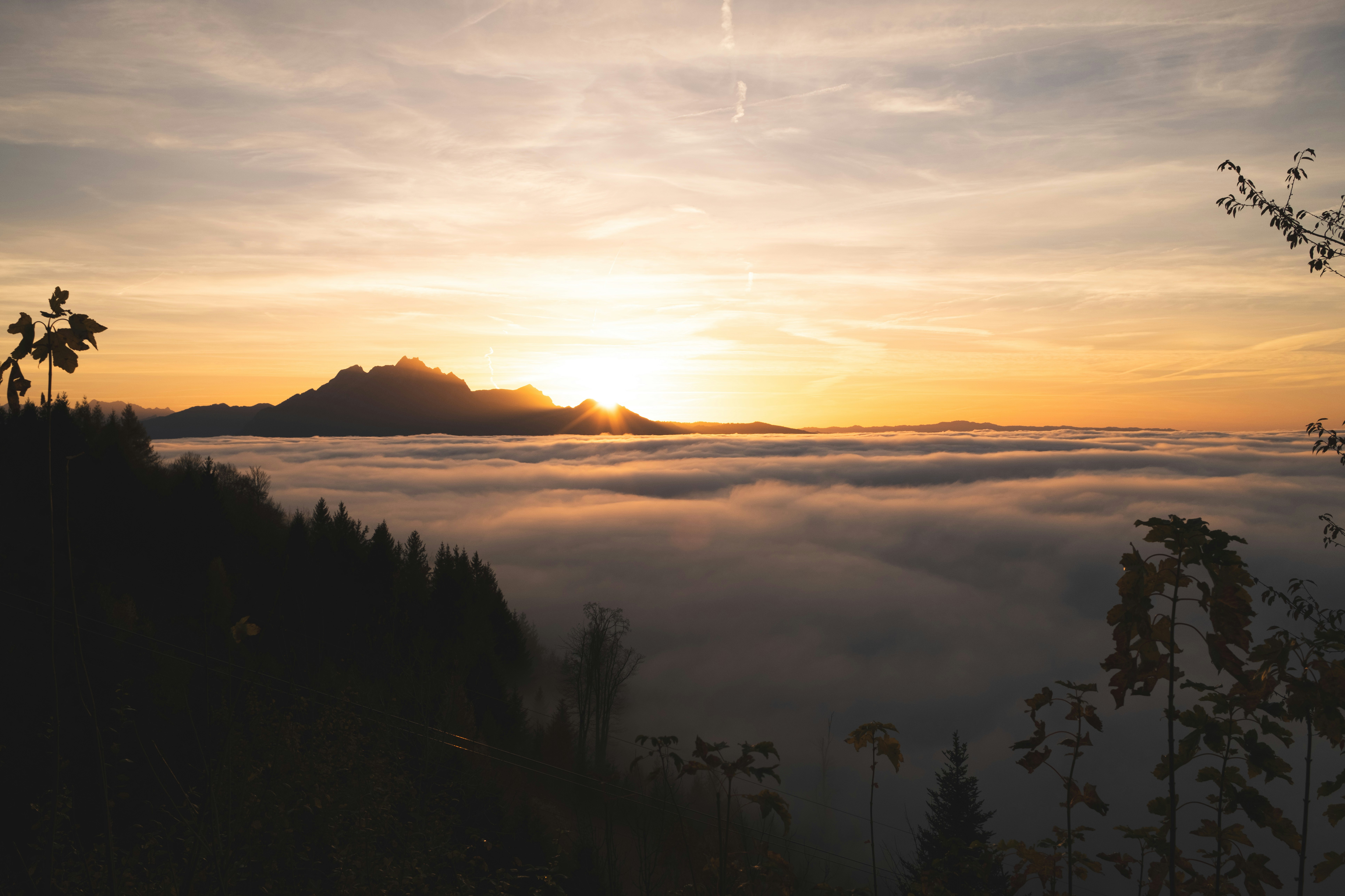 Sunrise over a sea of clouds with mountain peak.