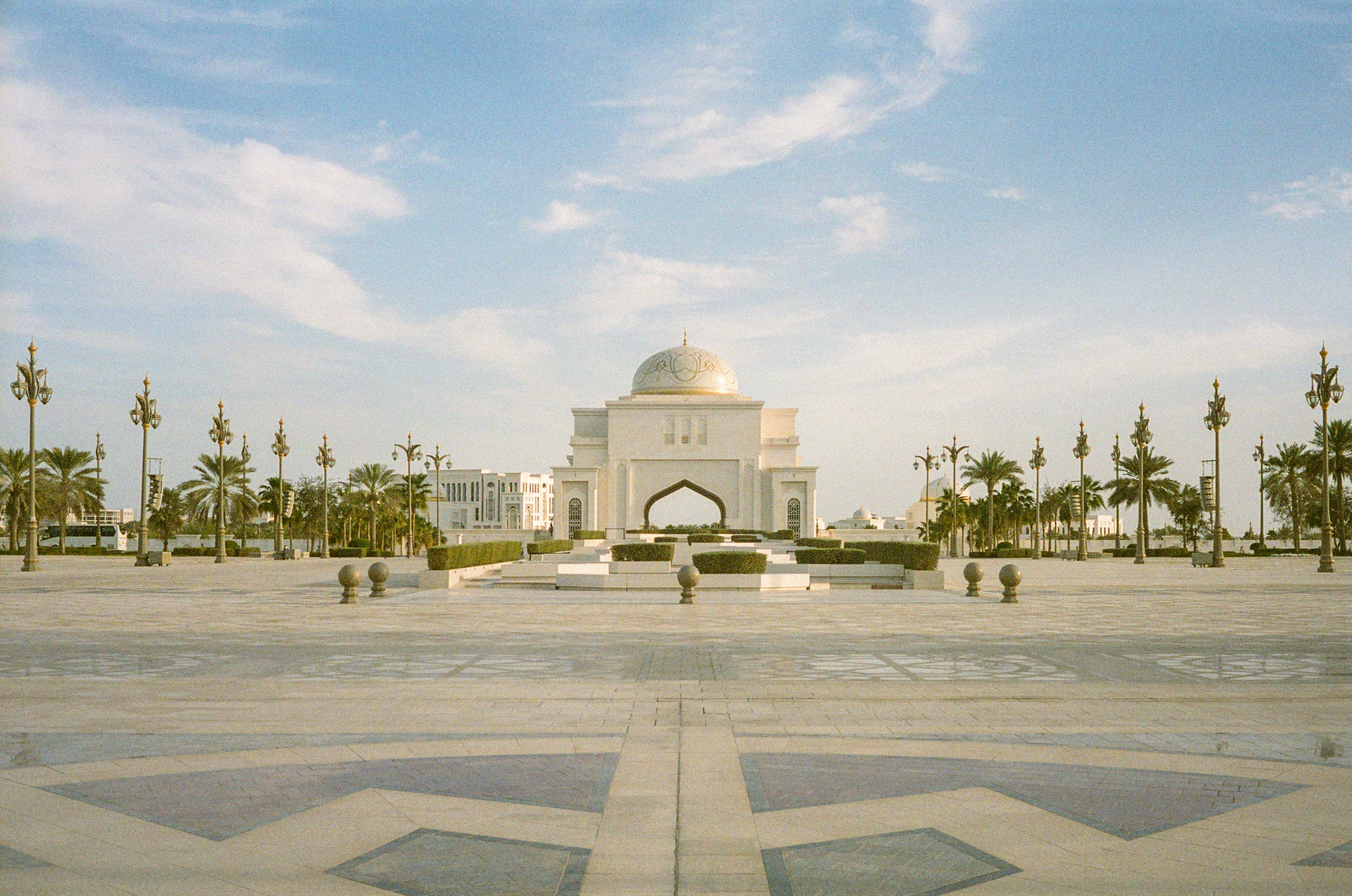 Grand building with dome and symmetrical palm trees.