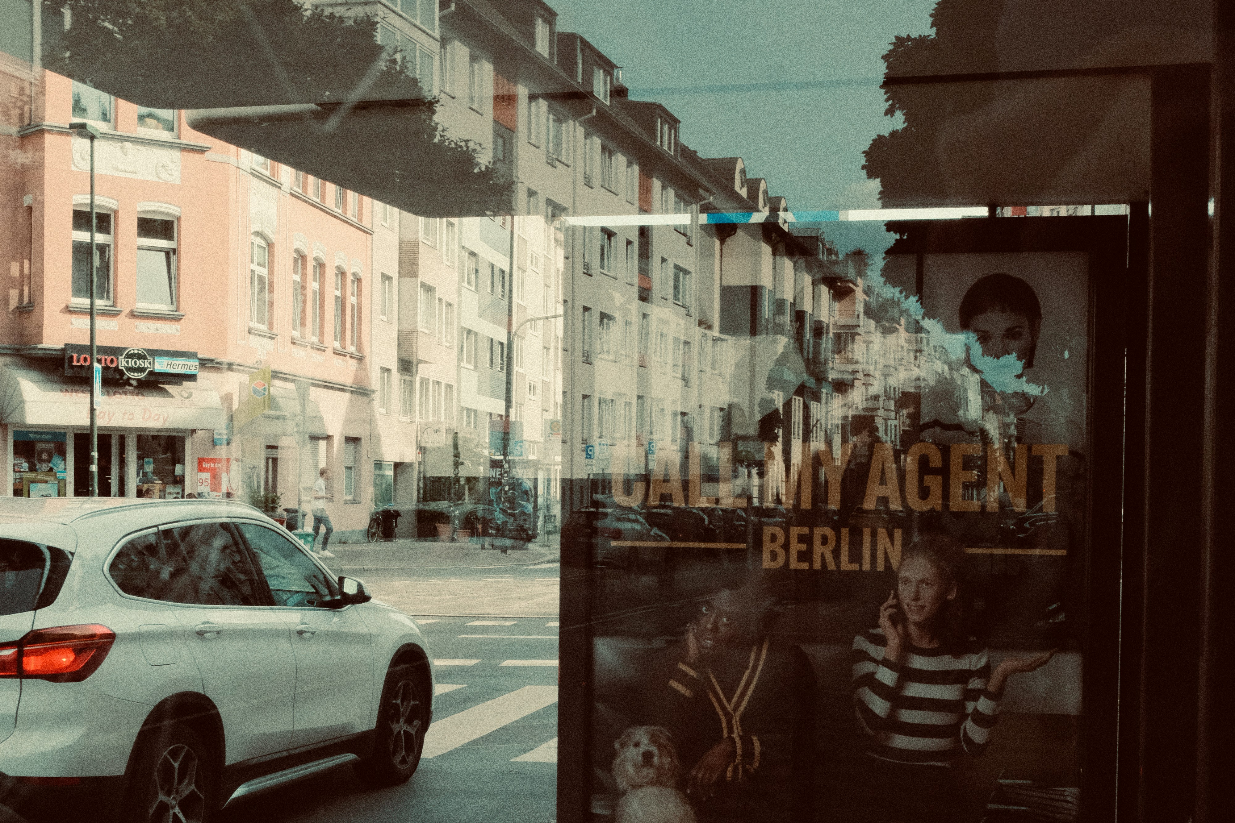 White car driving past a poster in a city