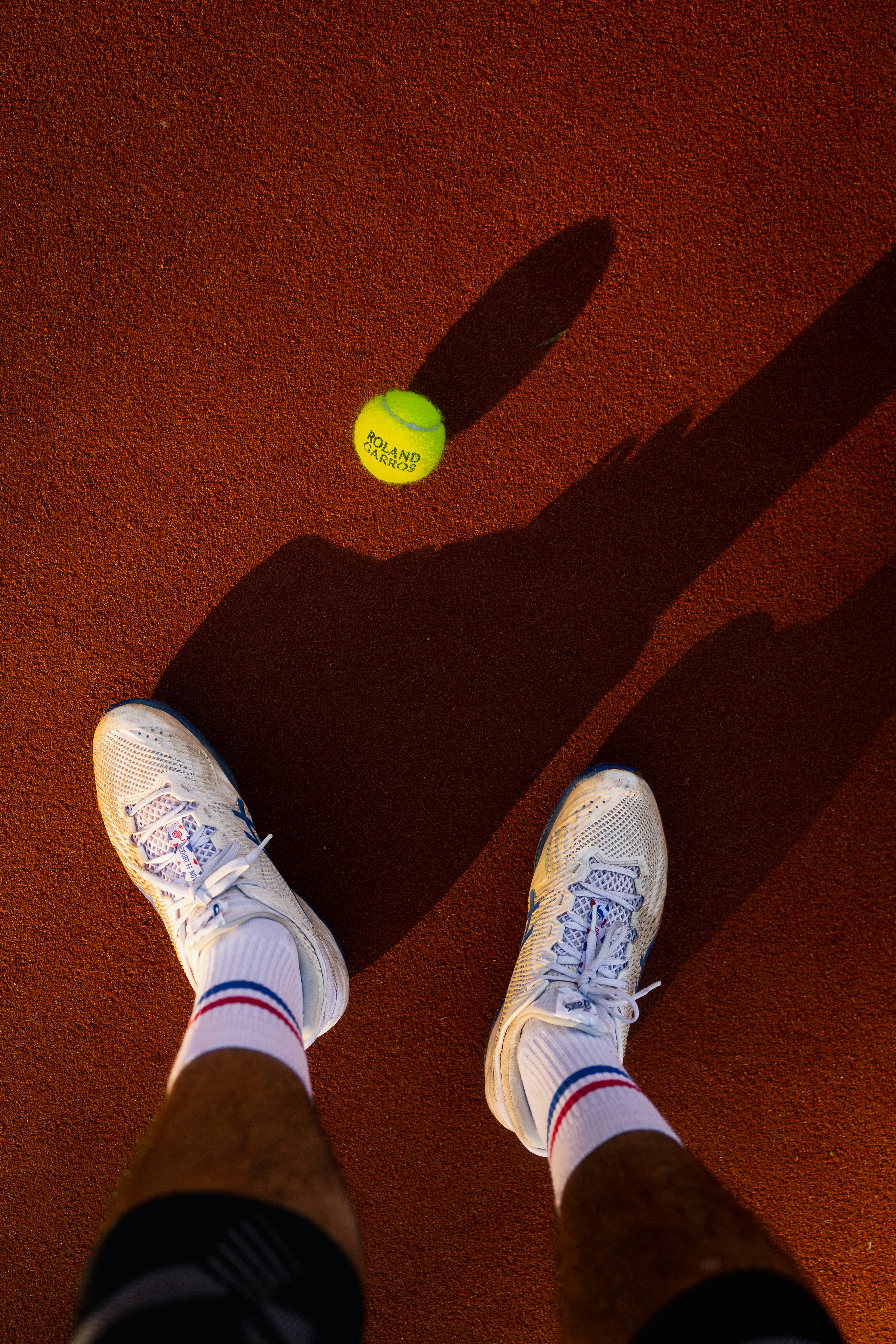 Tennis ball and player's feet on clay court