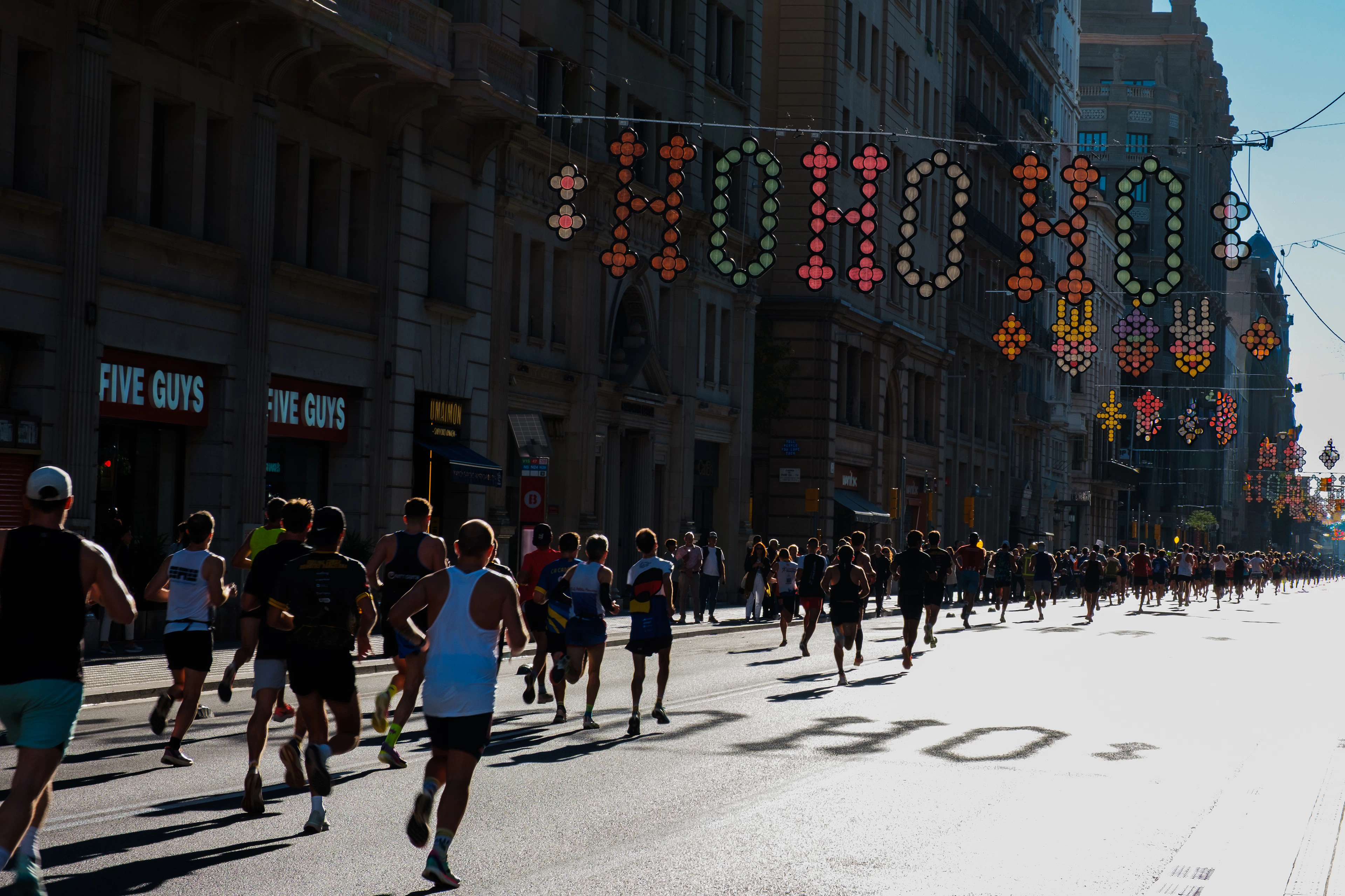 Runners racing down a city street lined with decorations, running Barcelona