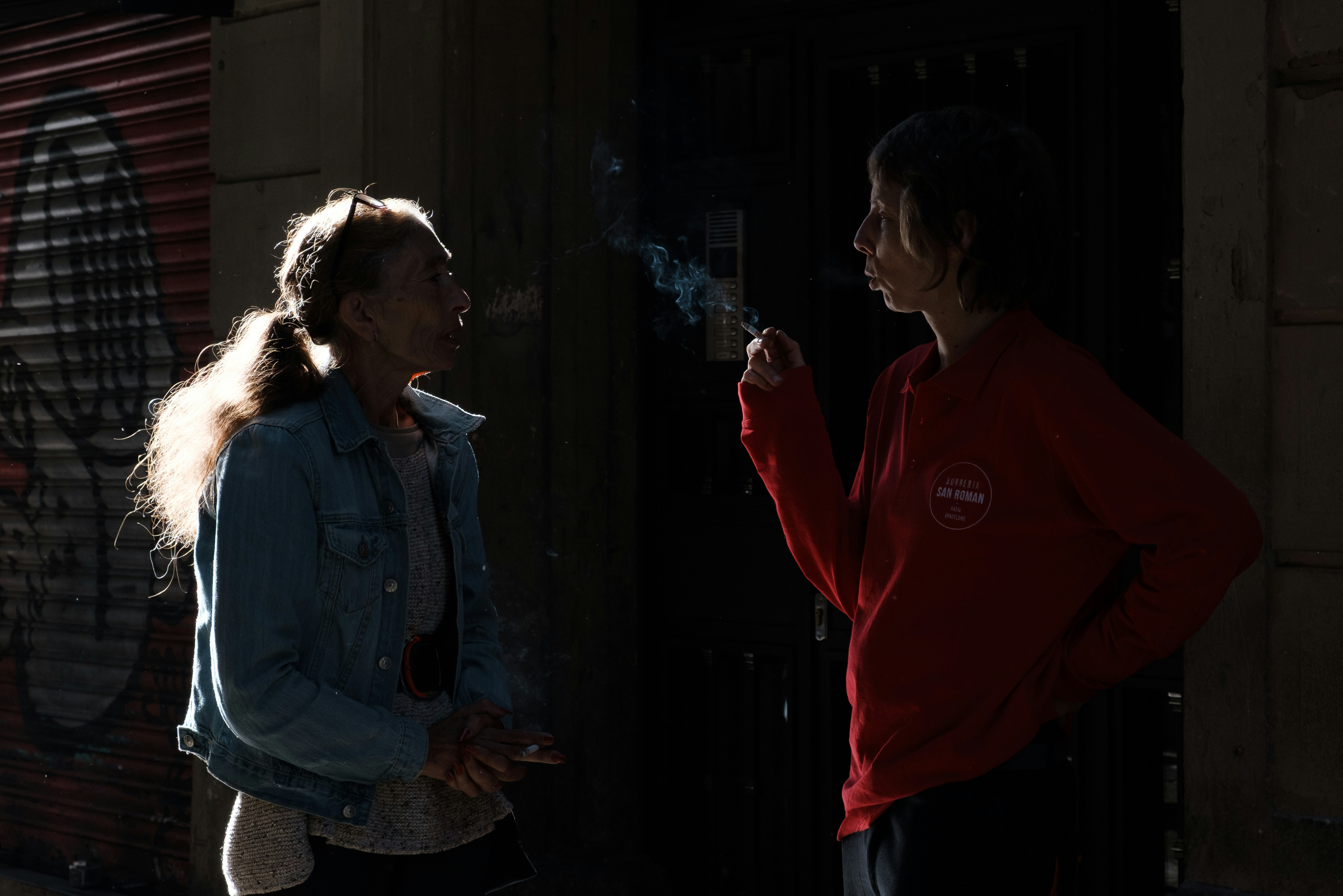Two people talking while smoking cigarettes.