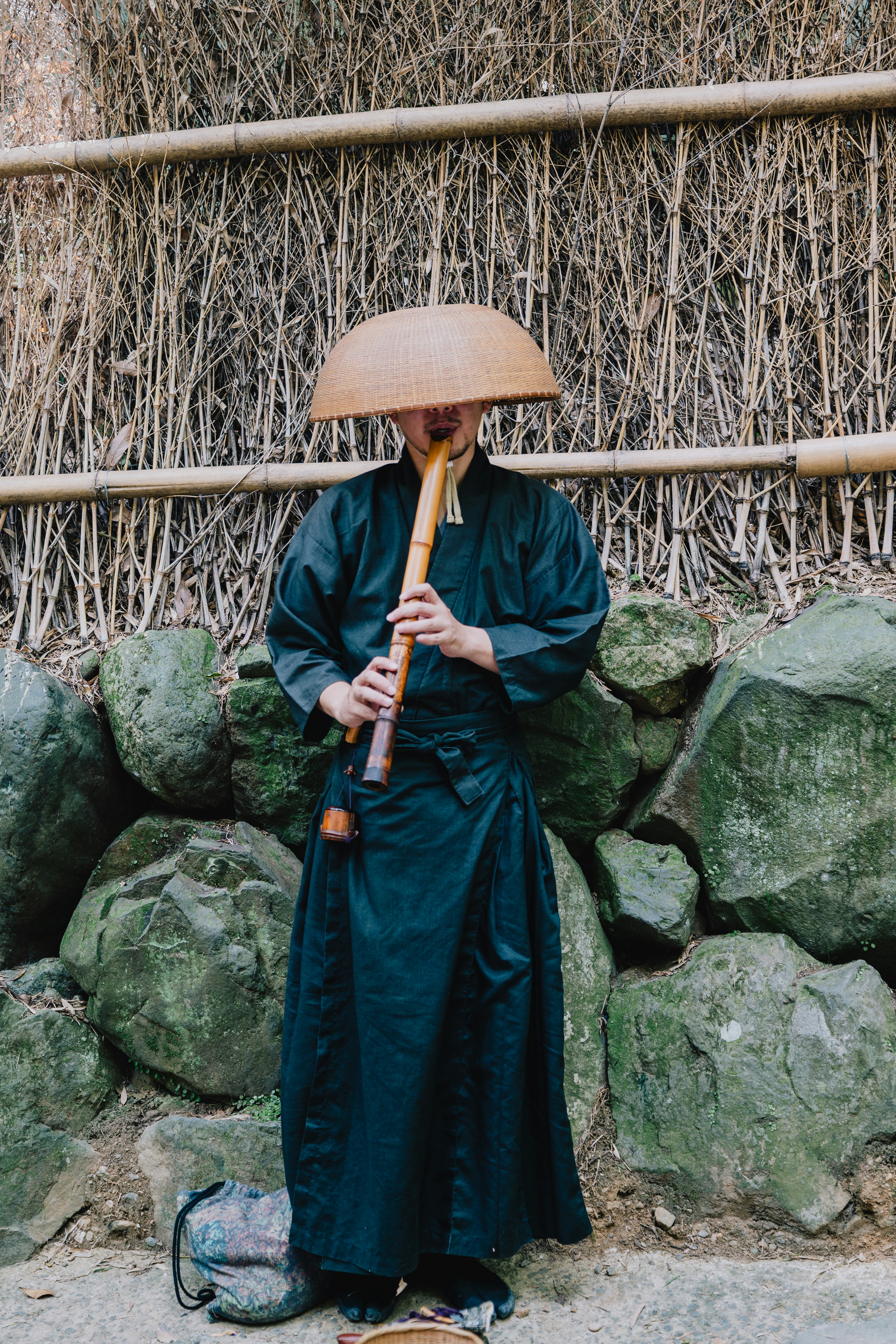 Musician in traditional japanese attire plays shakuhachi flute.