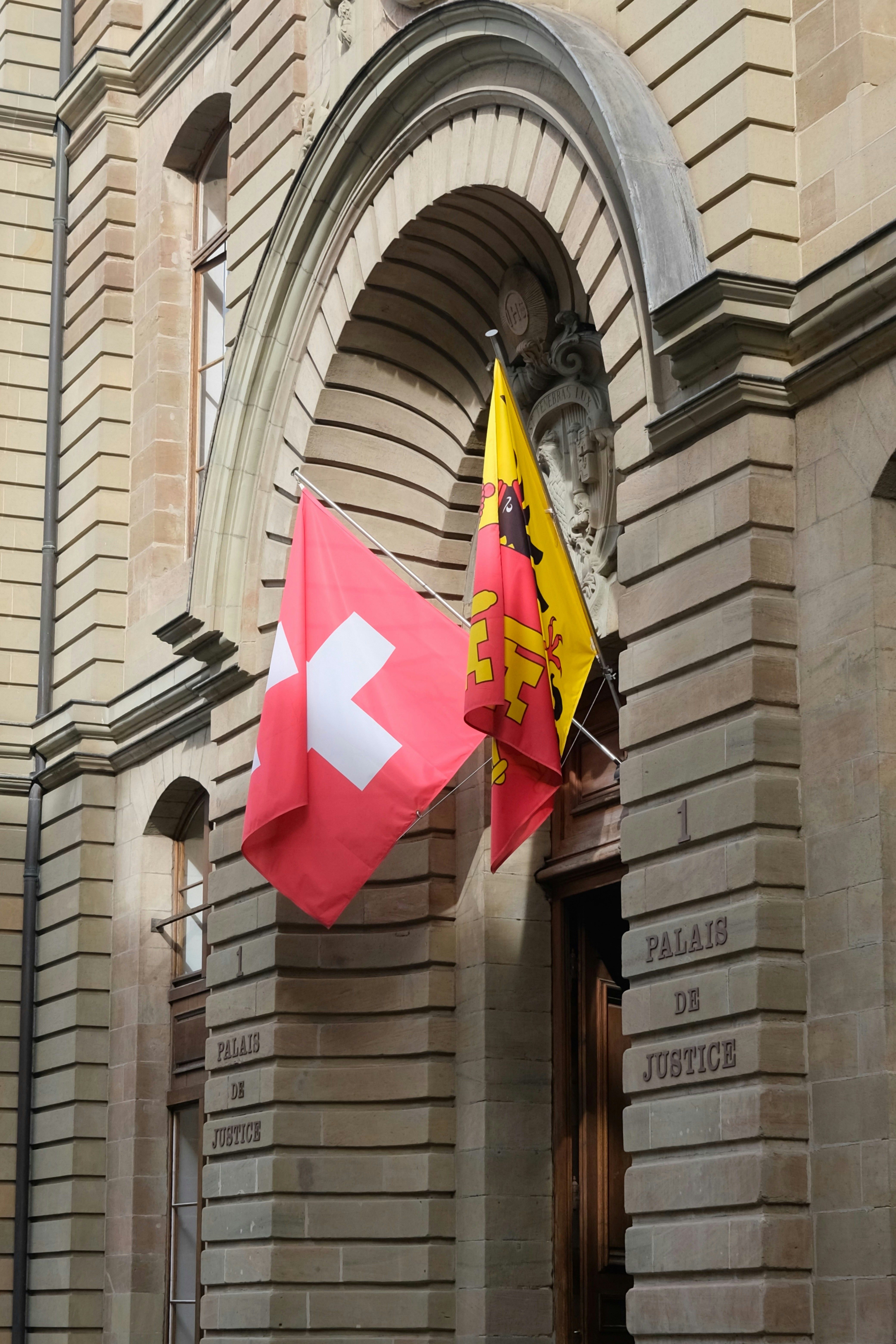 Swiss and geneva flags outside palais de justice.