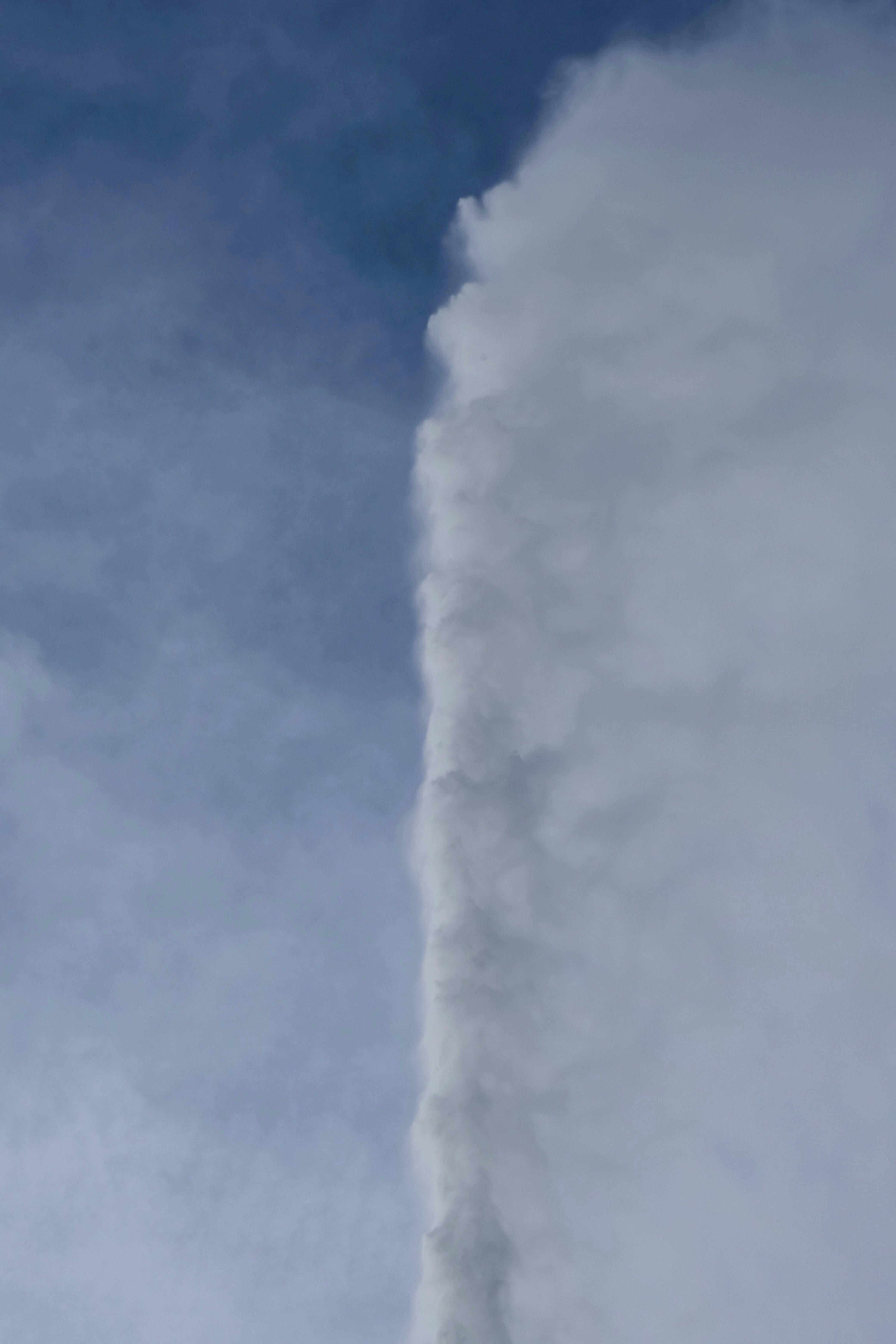 A geyser erupts against a blue sky