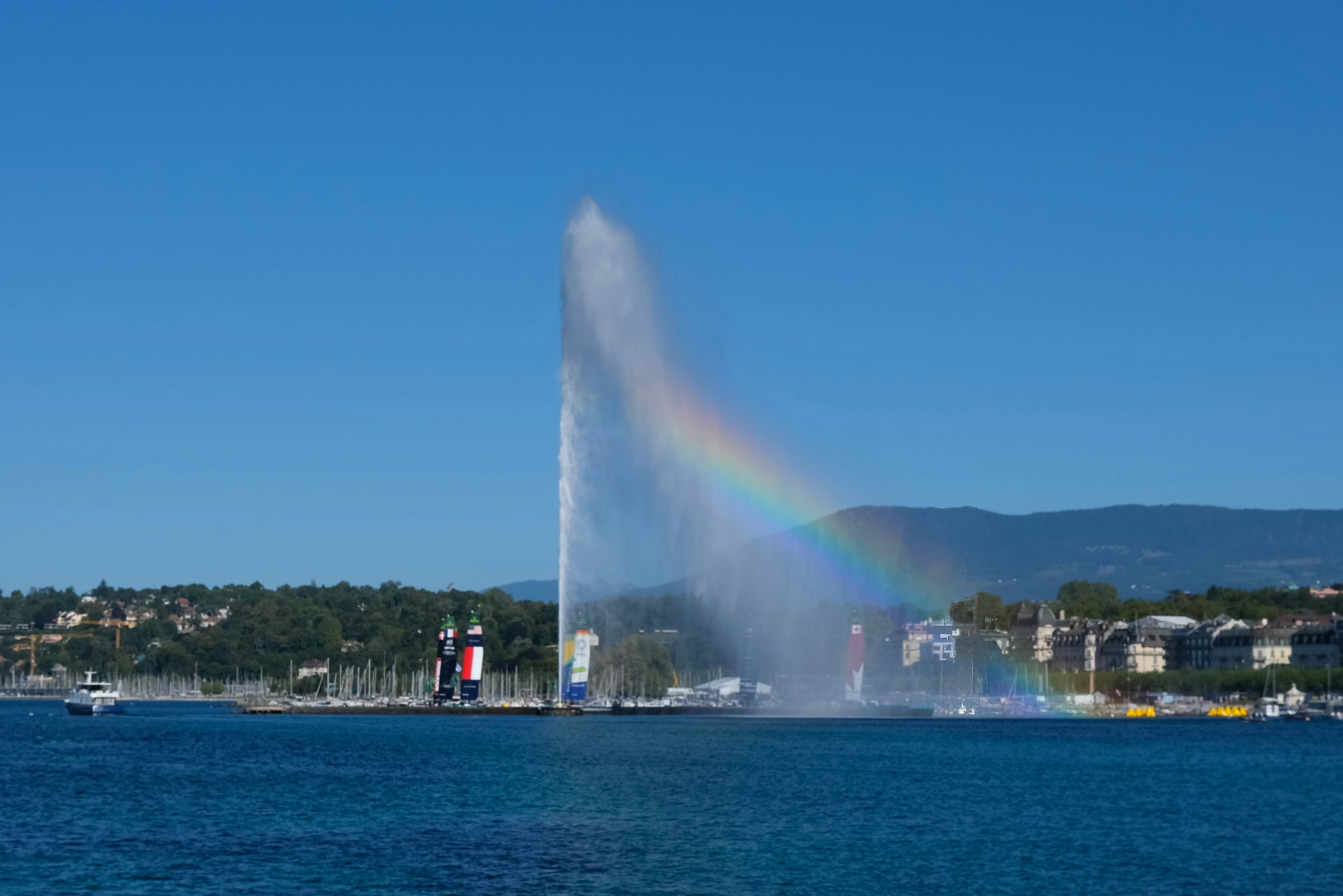 Large fountain spraying water with rainbow in lake.