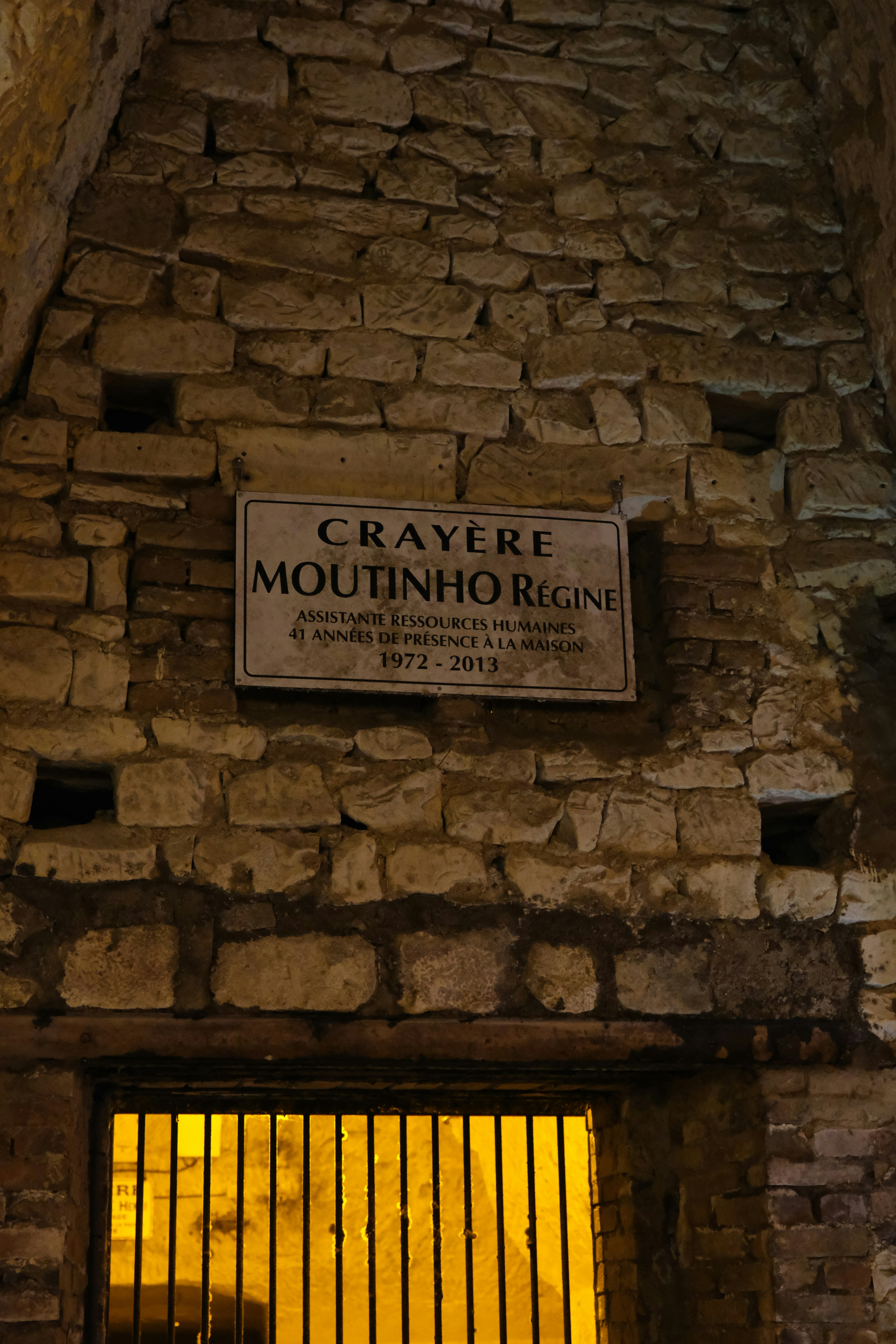 Muro in pietra con targa e ingresso sbarrato.