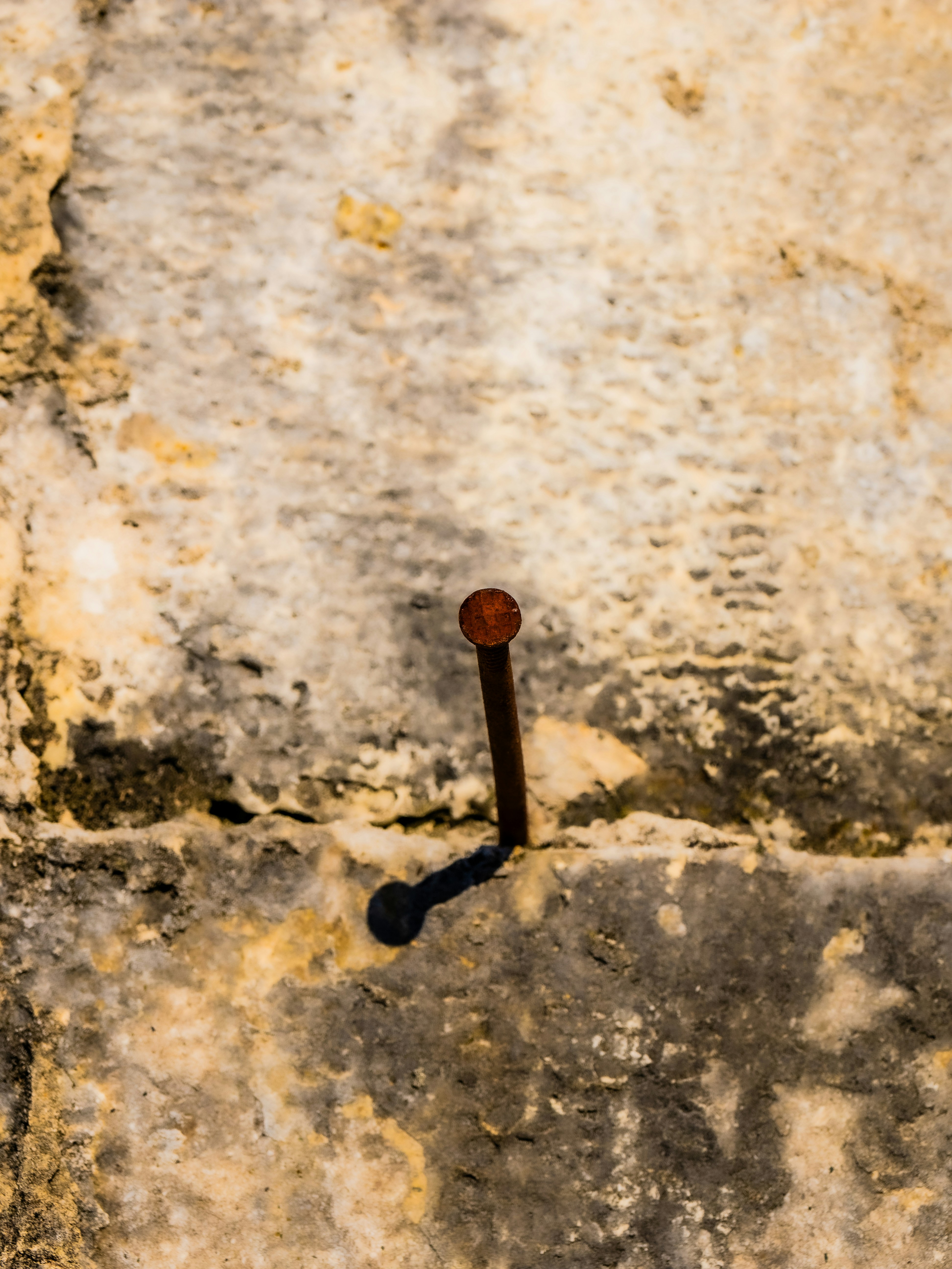 Rusty nail protruding from a textured stone wall