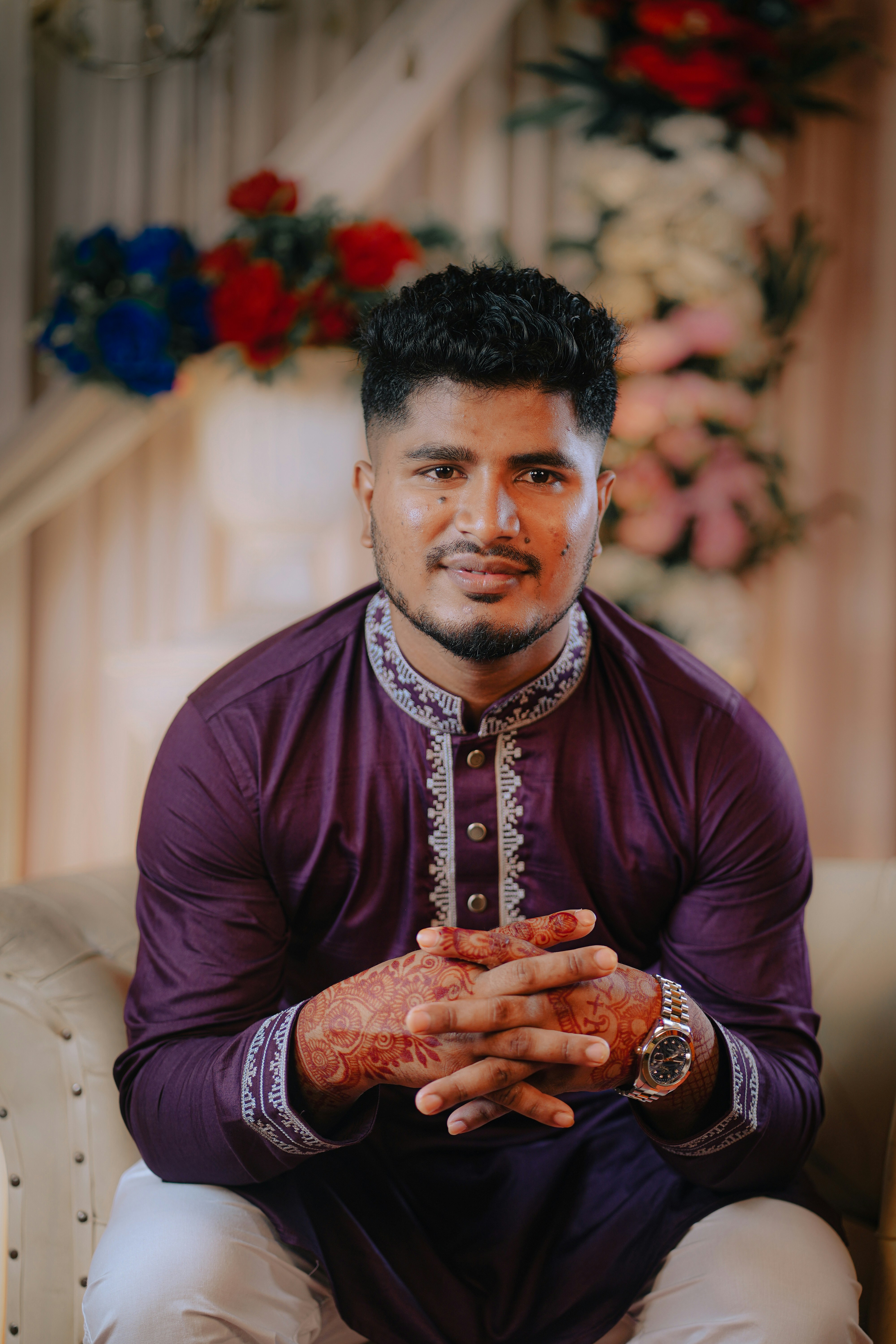 Seorang pria dengan kurta ungu duduk di sofa.