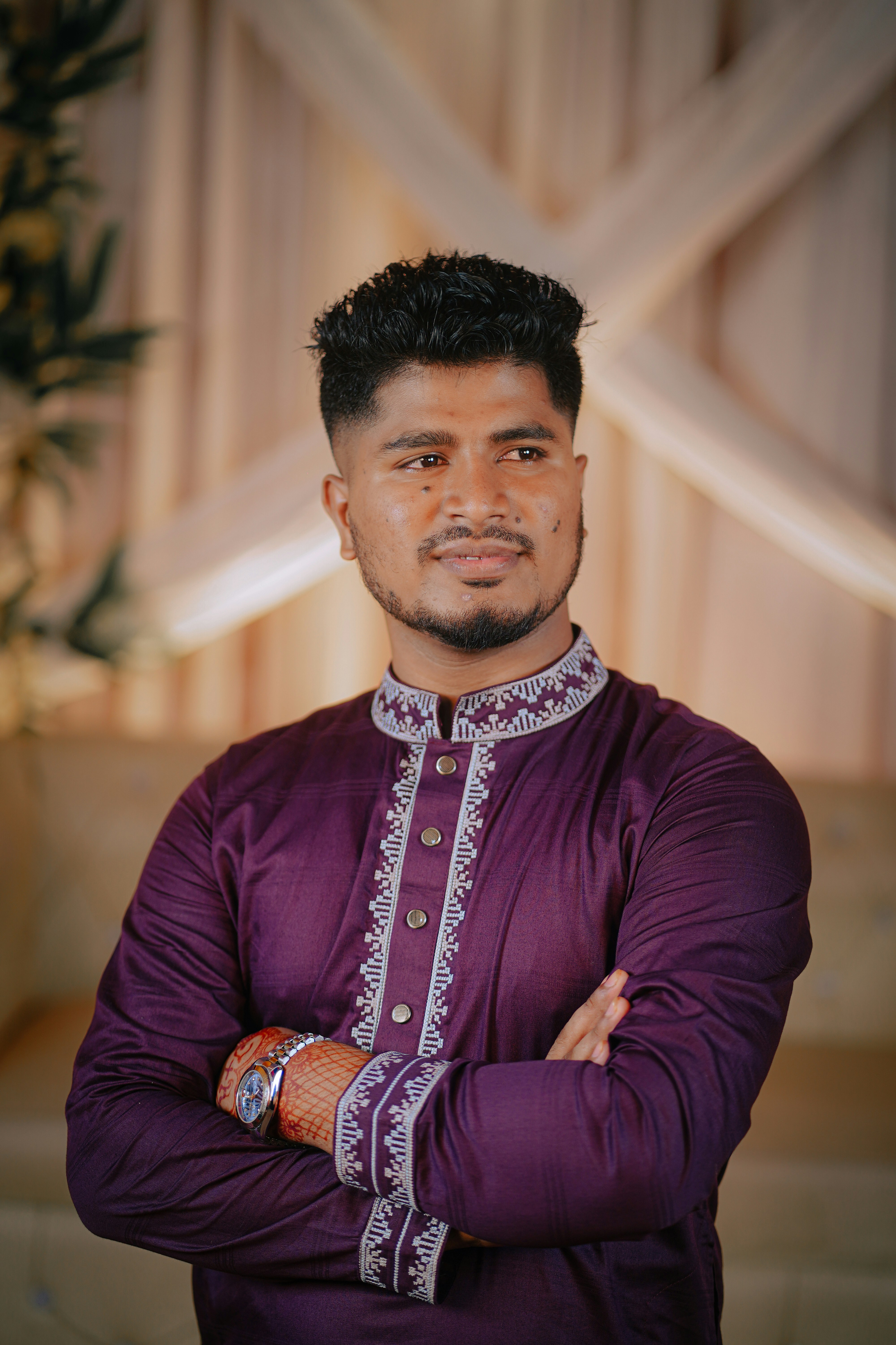 Homme en kurta violette avec les bras croisés.