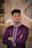 Man in purple kurta with arms crossed.