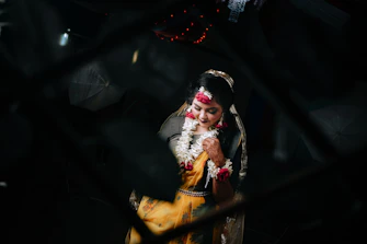 A woman in traditional attire with floral garlands.