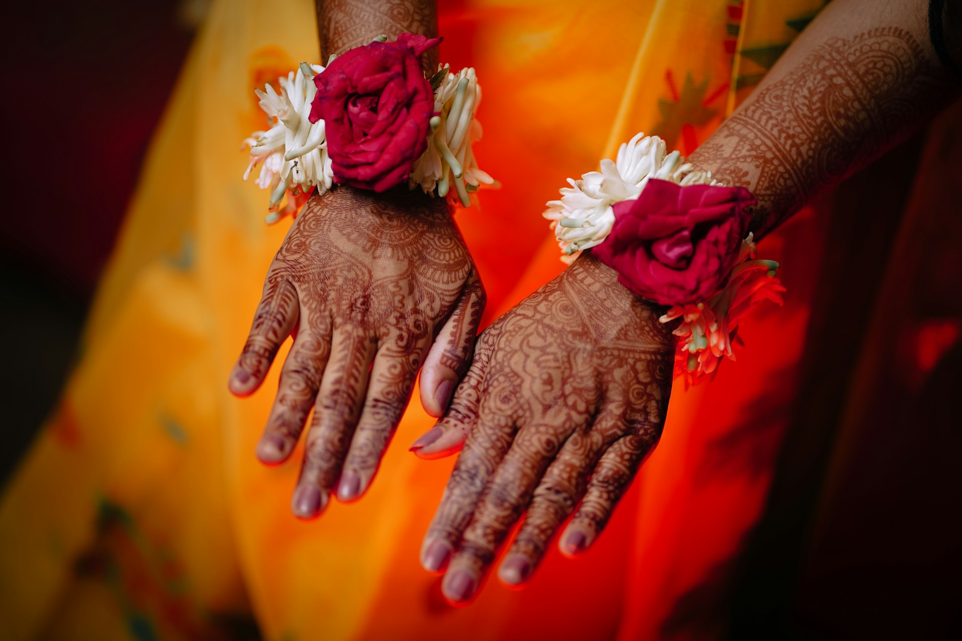 Hands adorned with henna and floral bracelets