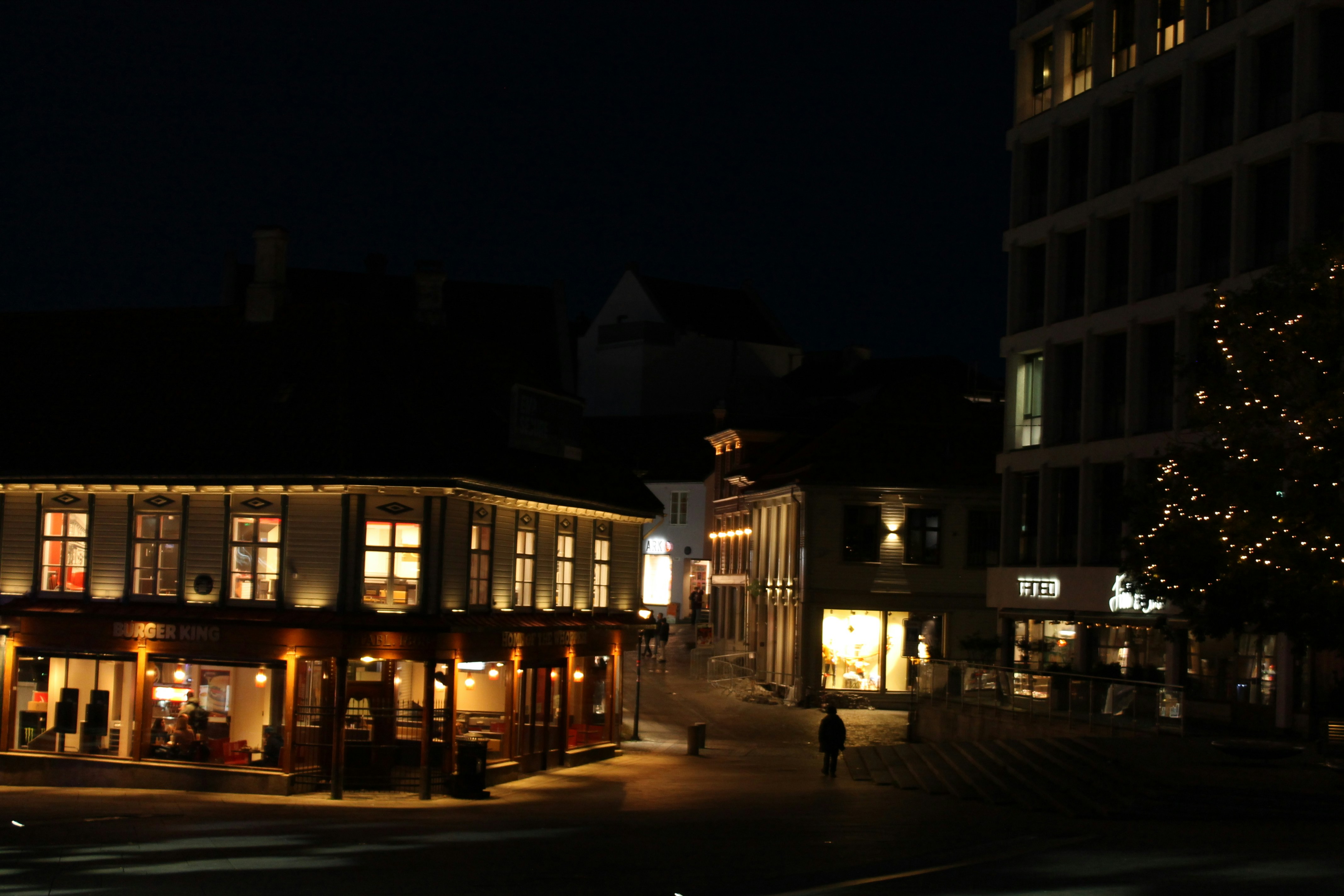 City street at night with illuminated buildings.