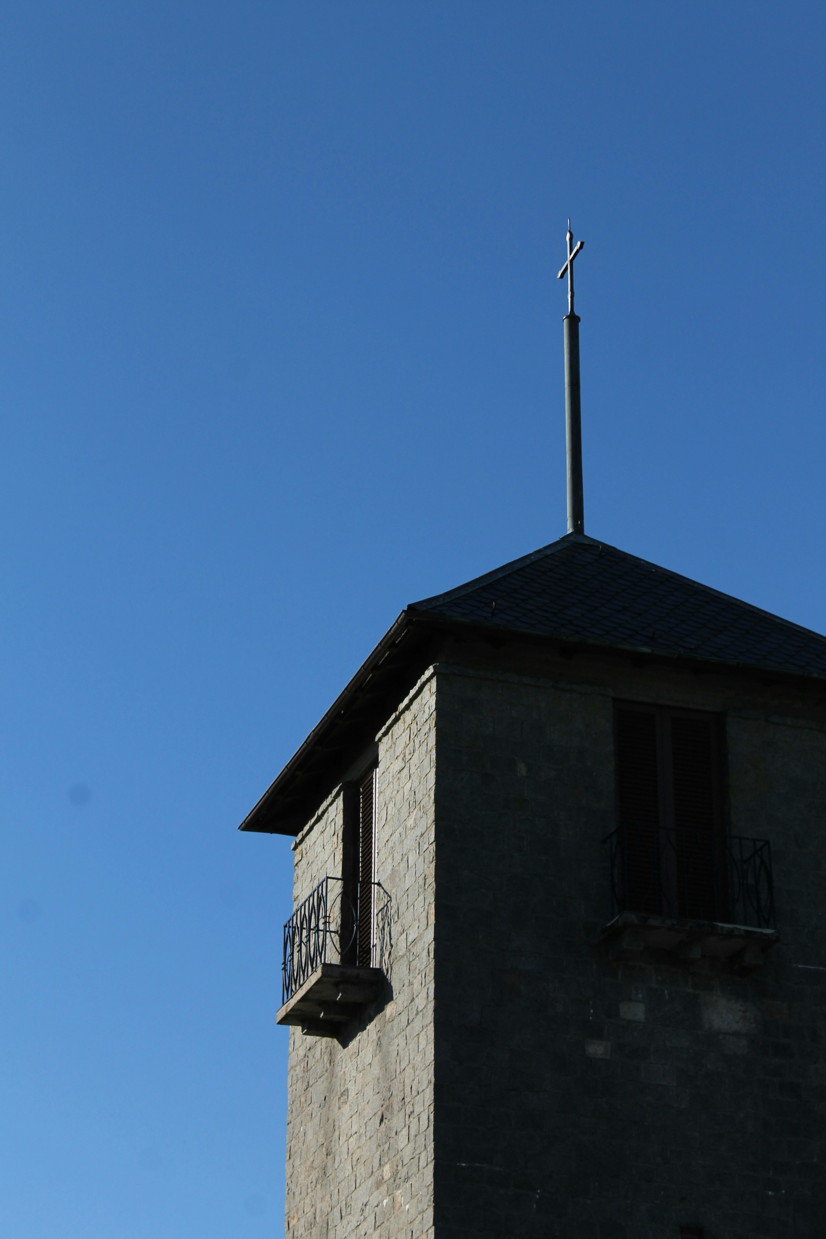 Stone tower with cross against clear blue sky